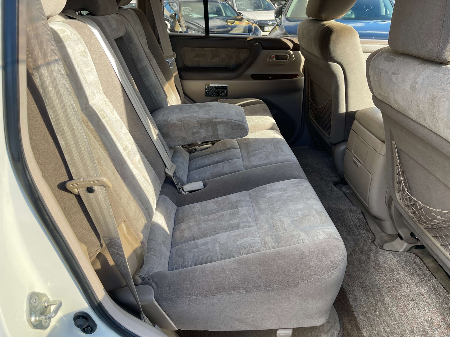 Interior seating of a 1998 Toyota Land Cruiser 100 VX Limited, showcasing comfortable rear seats and ample space.