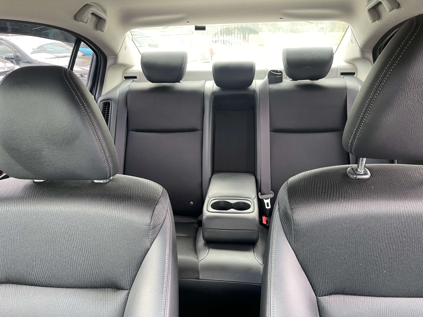 Interior view of the 2015 Honda Grace 1.5 Hybrid showing spacious seating for five and a central armrest with cup holders.