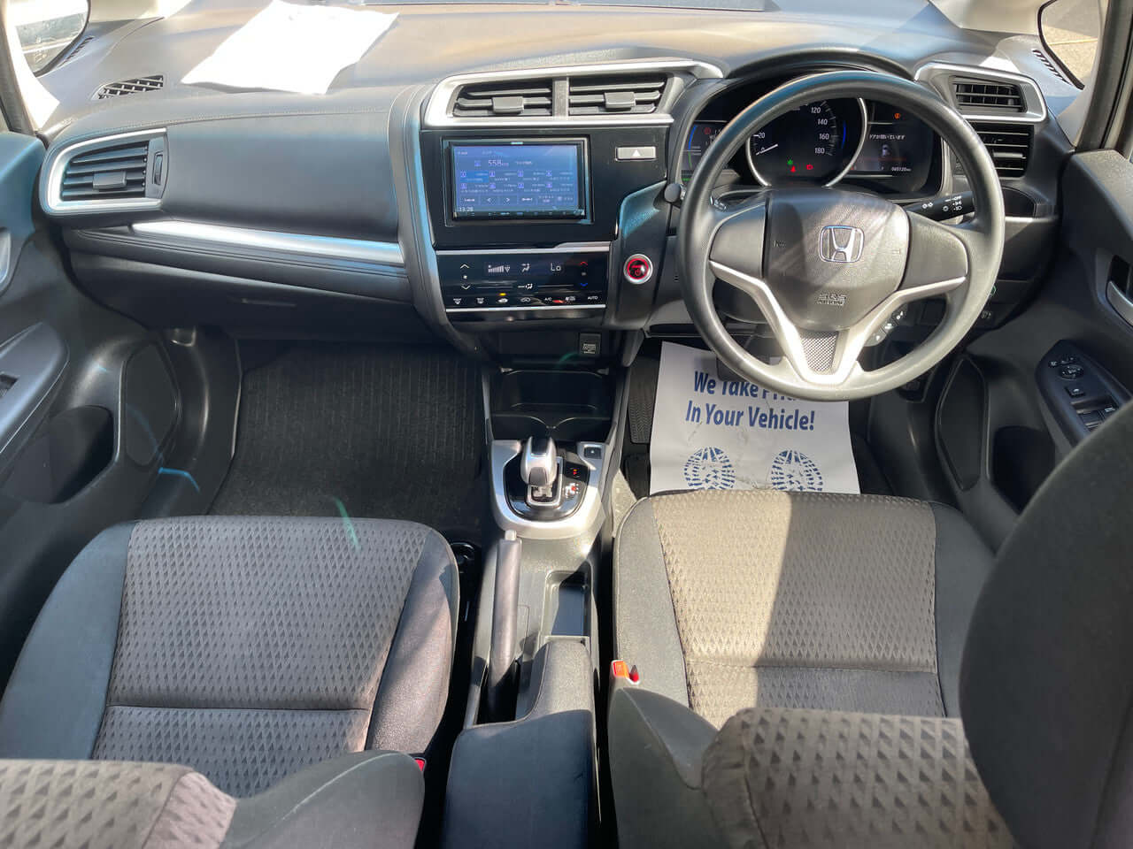 Interior view of a 2017 Honda Fit 1.5L Hybrid showing dashboard and front seats, highlighting its modern design.