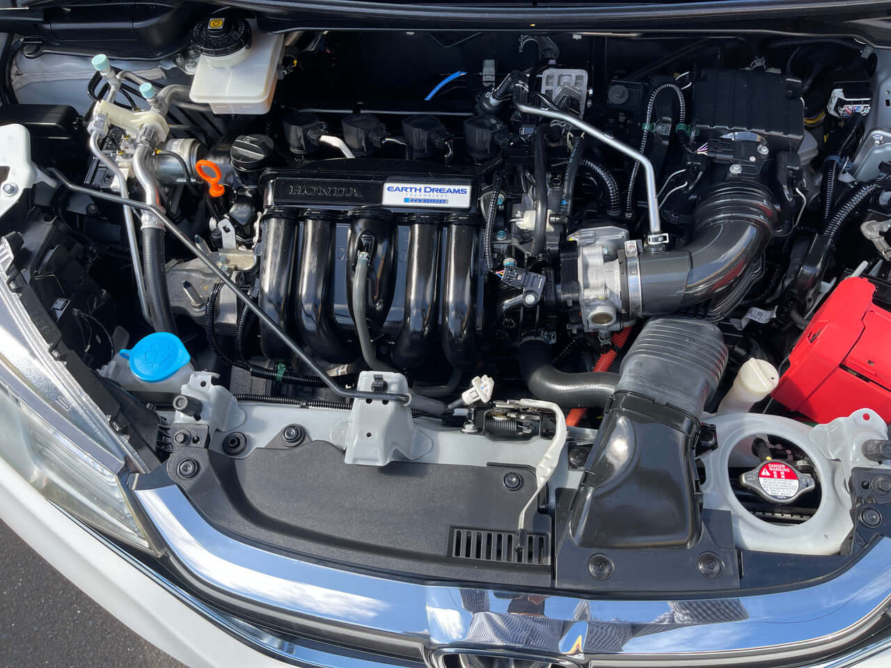 Engine bay of a 2017 Honda Fit 1.5L Hybrid showcasing engine components and performance features.