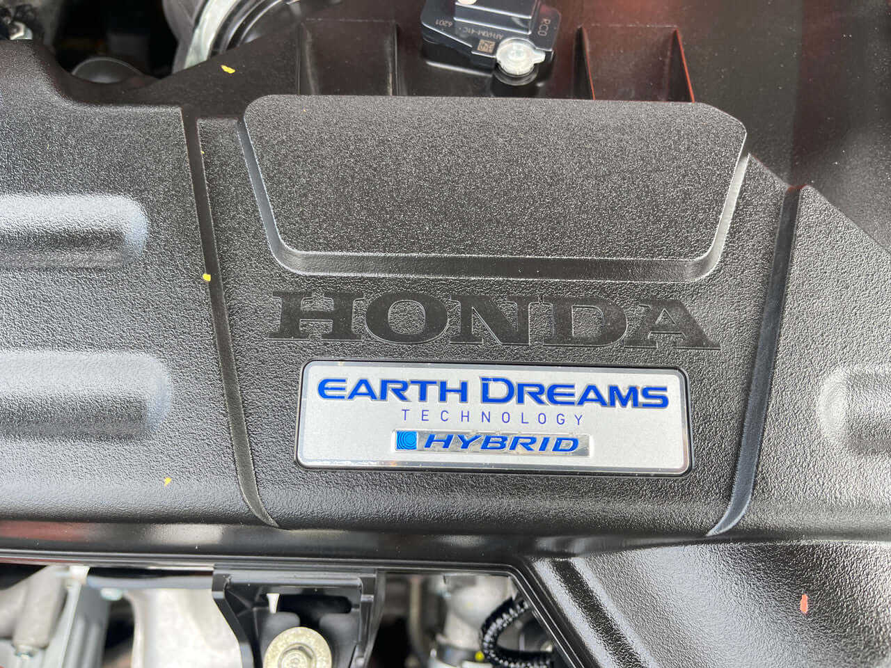2016 Honda Odyssey 2.0 Hybrid Close-up of Honda engine cover with Earth Dreams Technology emblem, featured in 2016 Honda Odyssey 2.0 Hybrid.