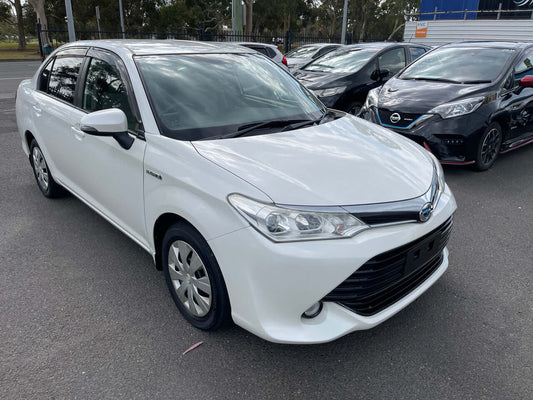 2015 Toyota Corolla Axio Hybrid 1.5L Sedan in white color parked on the street, showcasing its sleek design and hybrid efficiency.