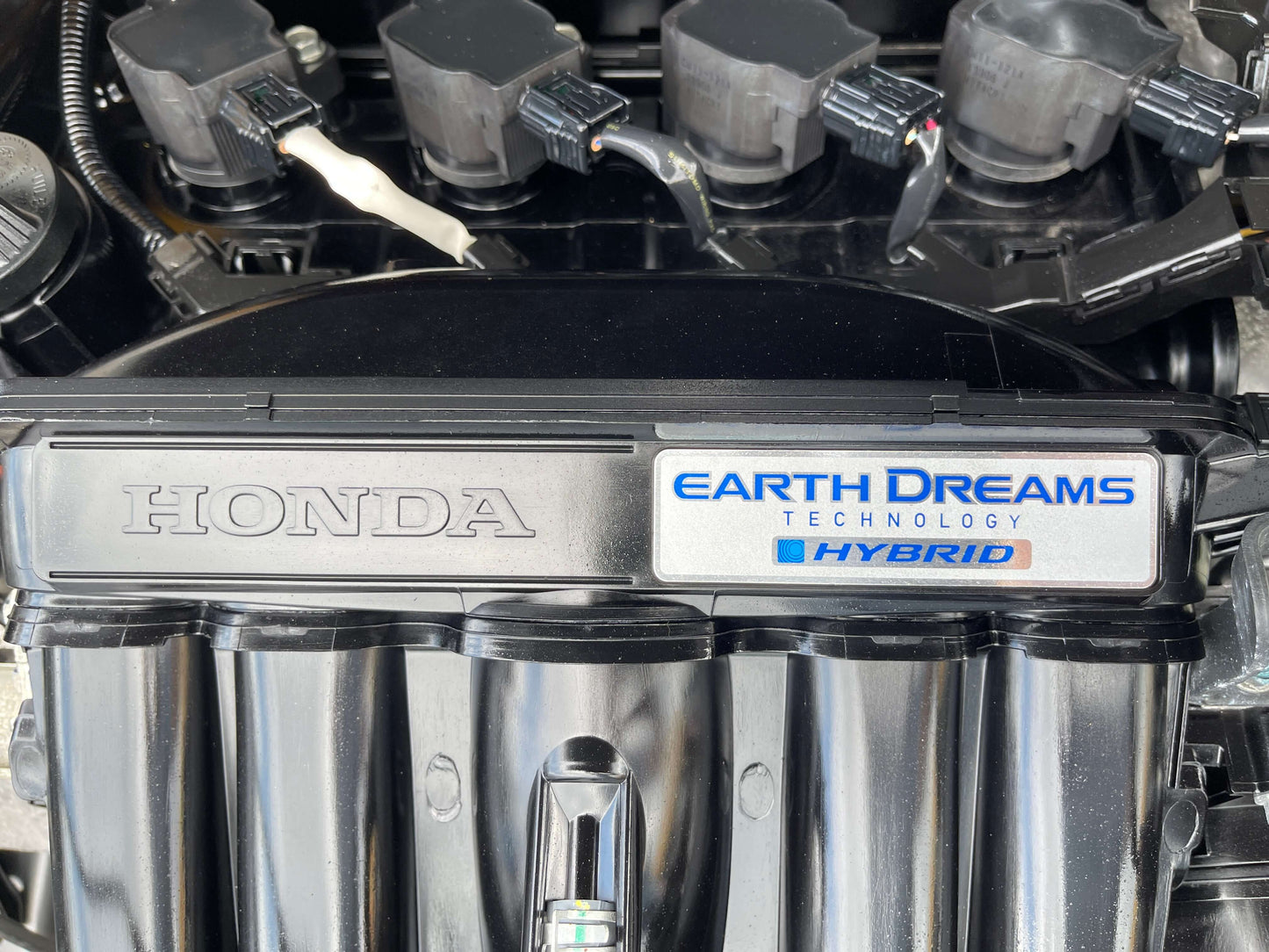 Close-up of the engine cover featuring Honda Earth Dreams Technology Hybrid label for 2019 Honda Shuttle 1.5L 4WD Hybrid.