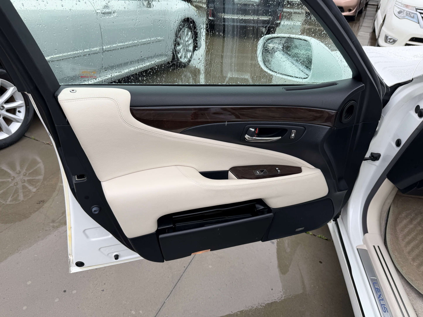 Interior view of 2007 Lexus LS600h AWD V8 5.0L Hybrid door panel with luxury trim and rain droplets.