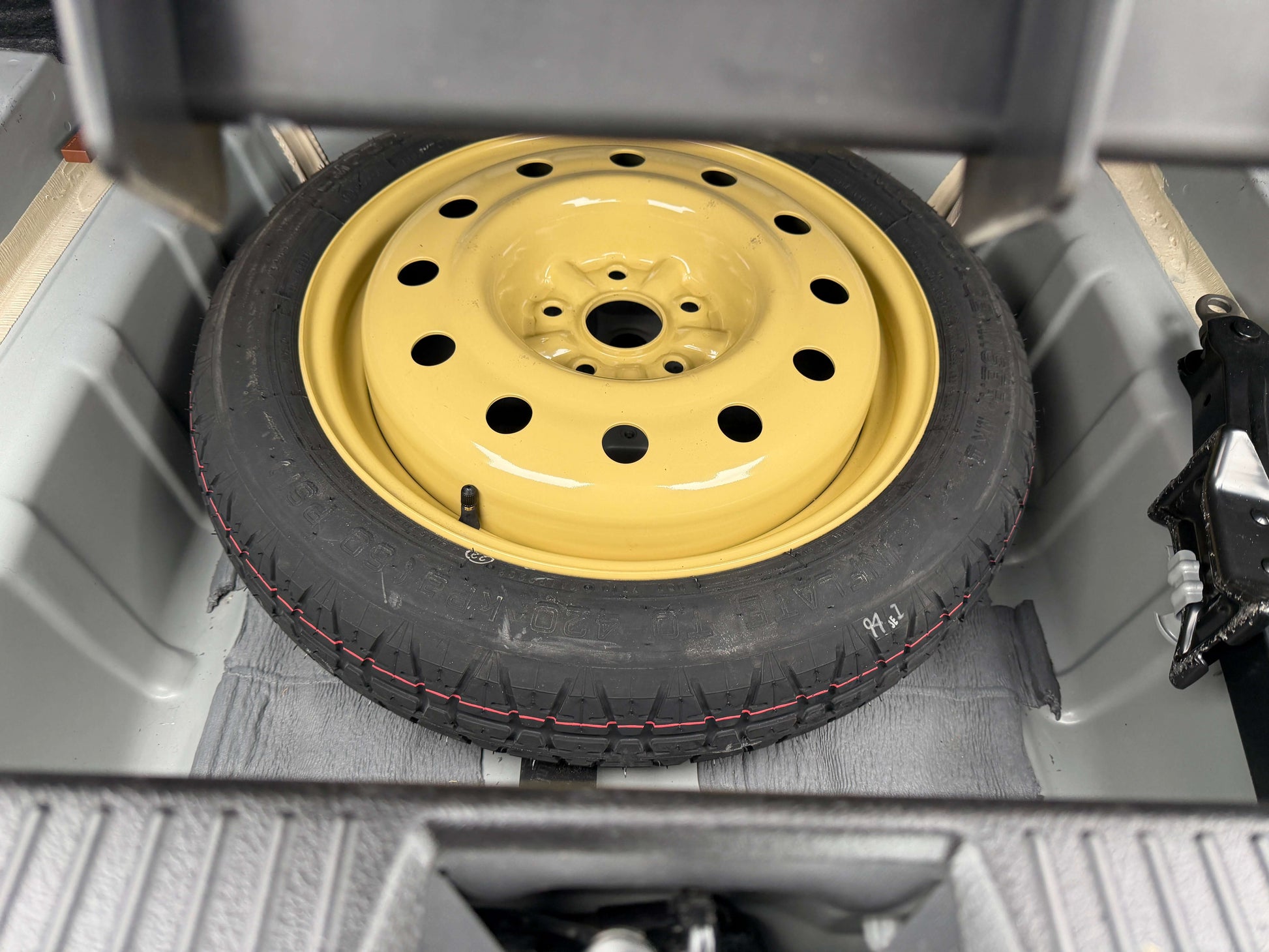 2008 Toyota Crown V6 3.0L Spare tire and yellow wheel located in the trunk of a vehicle.