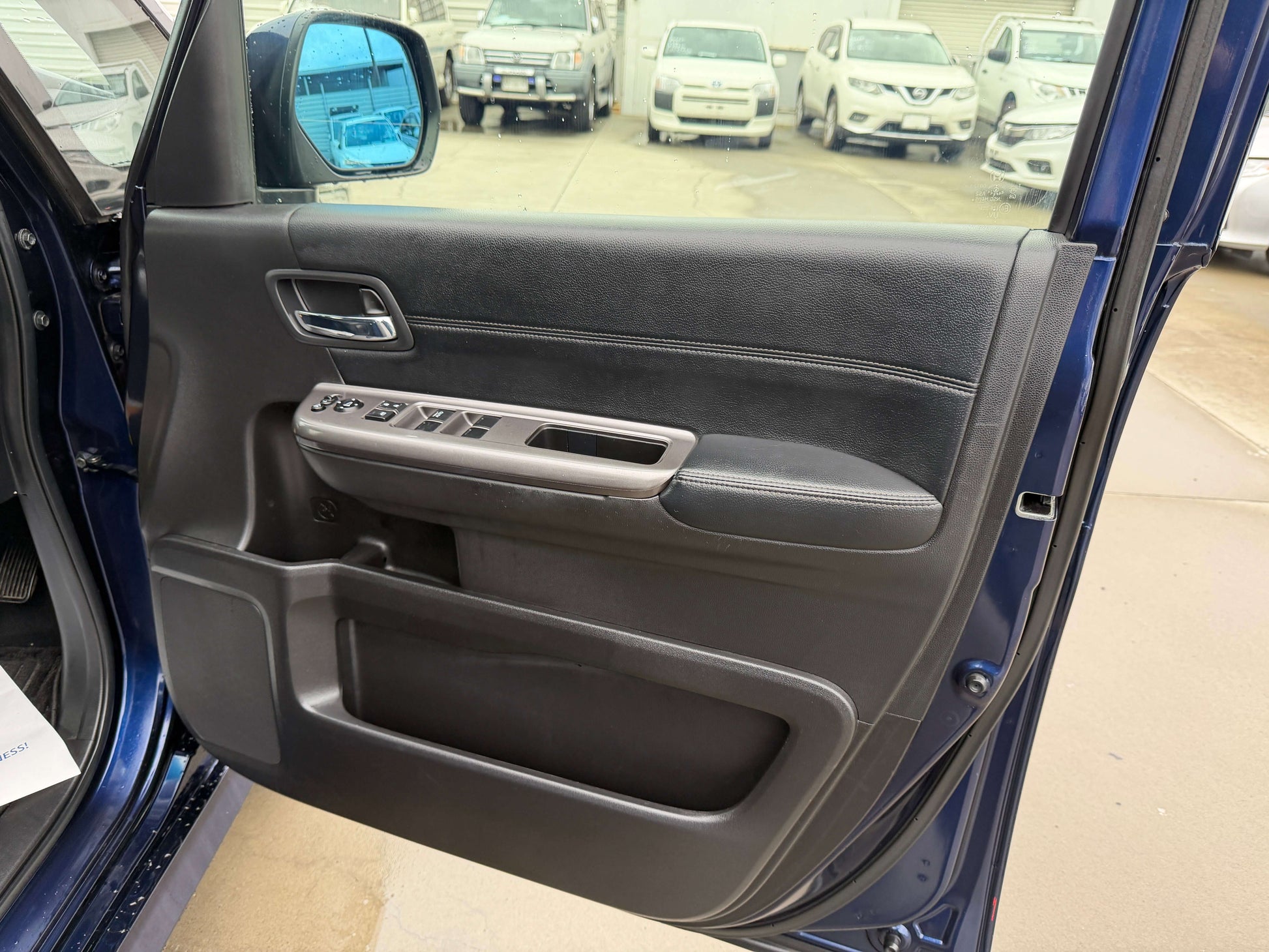 Interior view of the driver side door panel of the 2018 Honda Honda Stepwgn 2.0 Spada Hybrid, showcasing controls and handle.