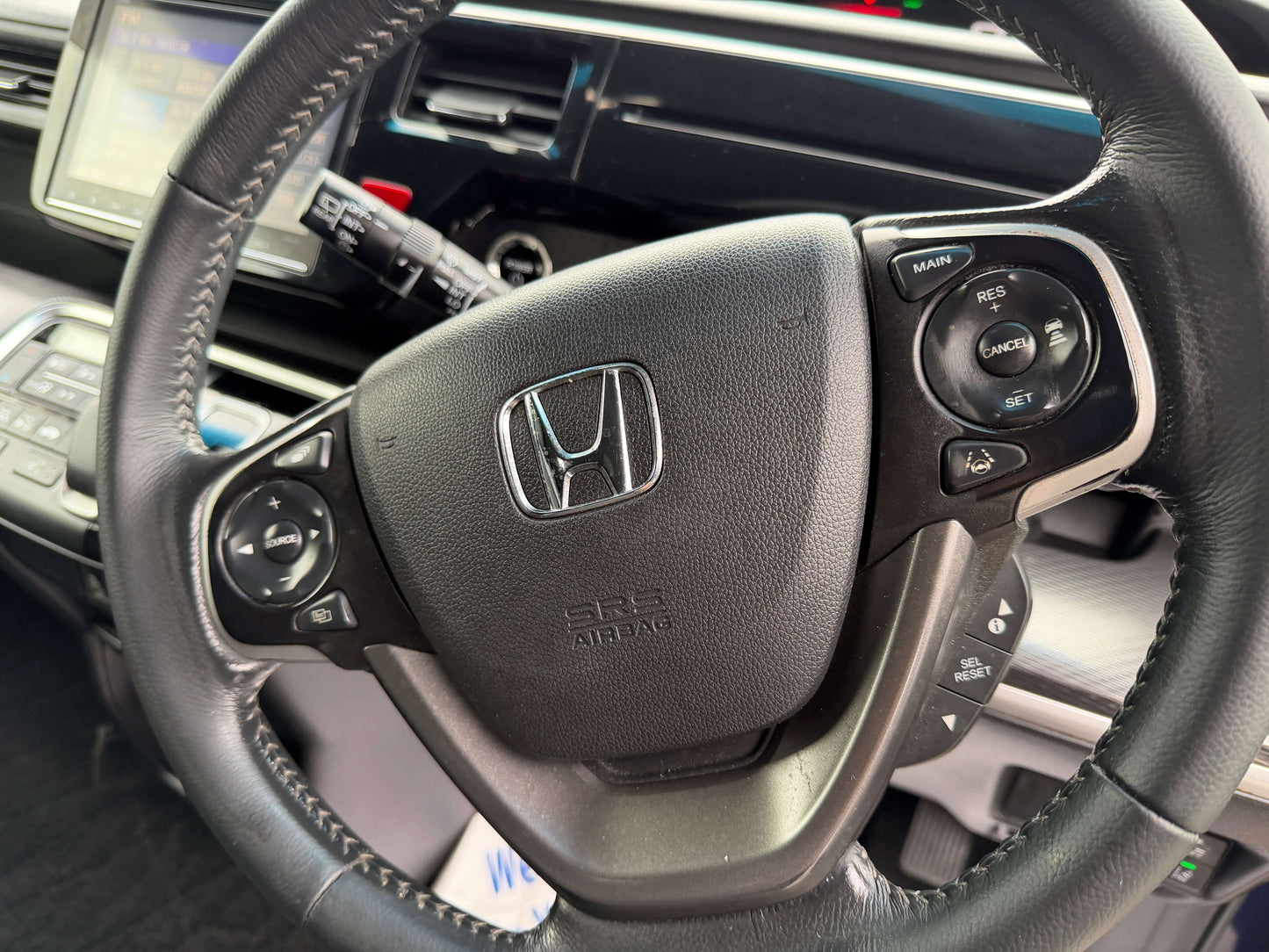 2018 Honda Honda Stepwgn 2.0 Spada Hybrid steering wheel with controls and logo in interior view.