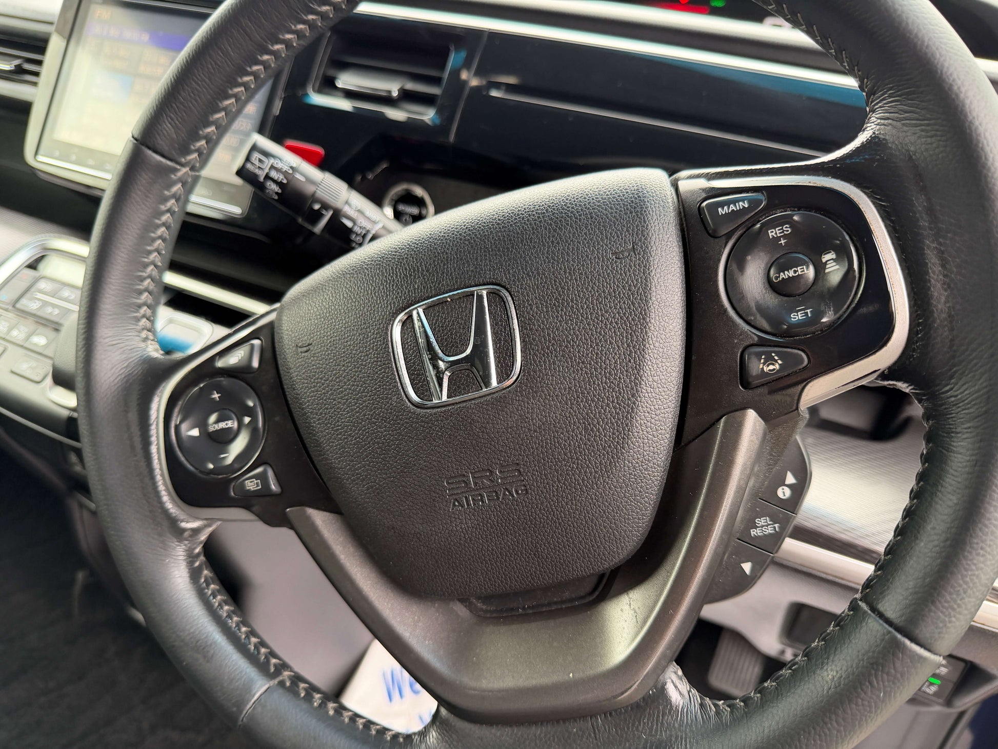 2018 Honda Honda Stepwgn 2.0 Spada Hybrid steering wheel with controls and logo in interior view.