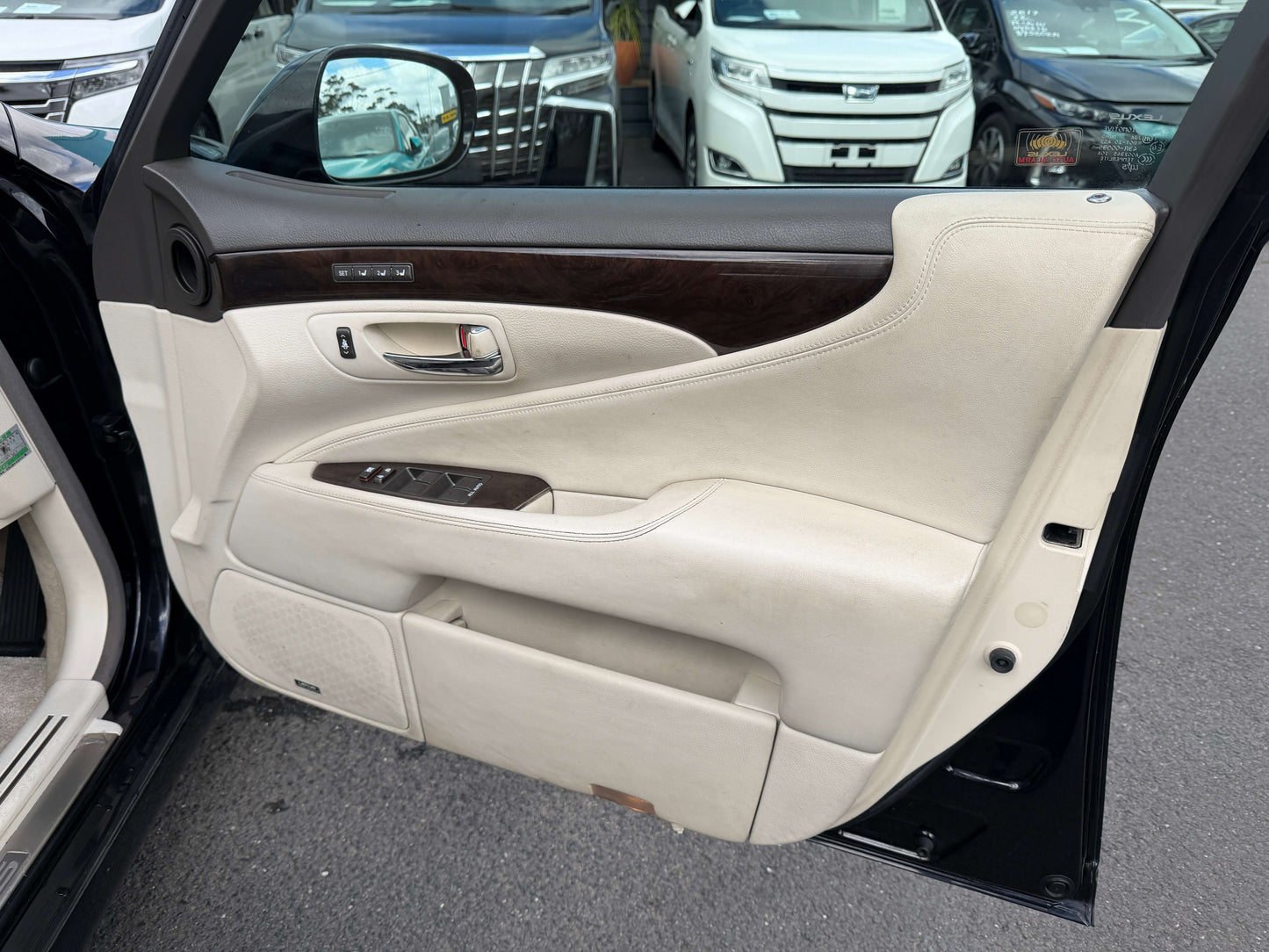 Interior view of the 2007 Lexus LS600h AWD V8 5.0L Hybrid luxury sedan door panel, featuring cream leather and wood accents.