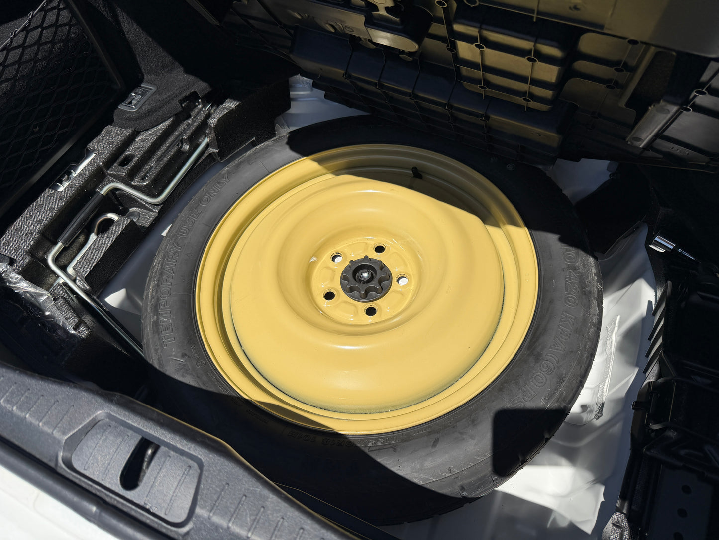 2007 Lexus LS600hL AWD V8 5.0L Hybrid Spare tire in the trunk of a vehicle, featuring a yellow rim, showcasing vehicle maintenance options.