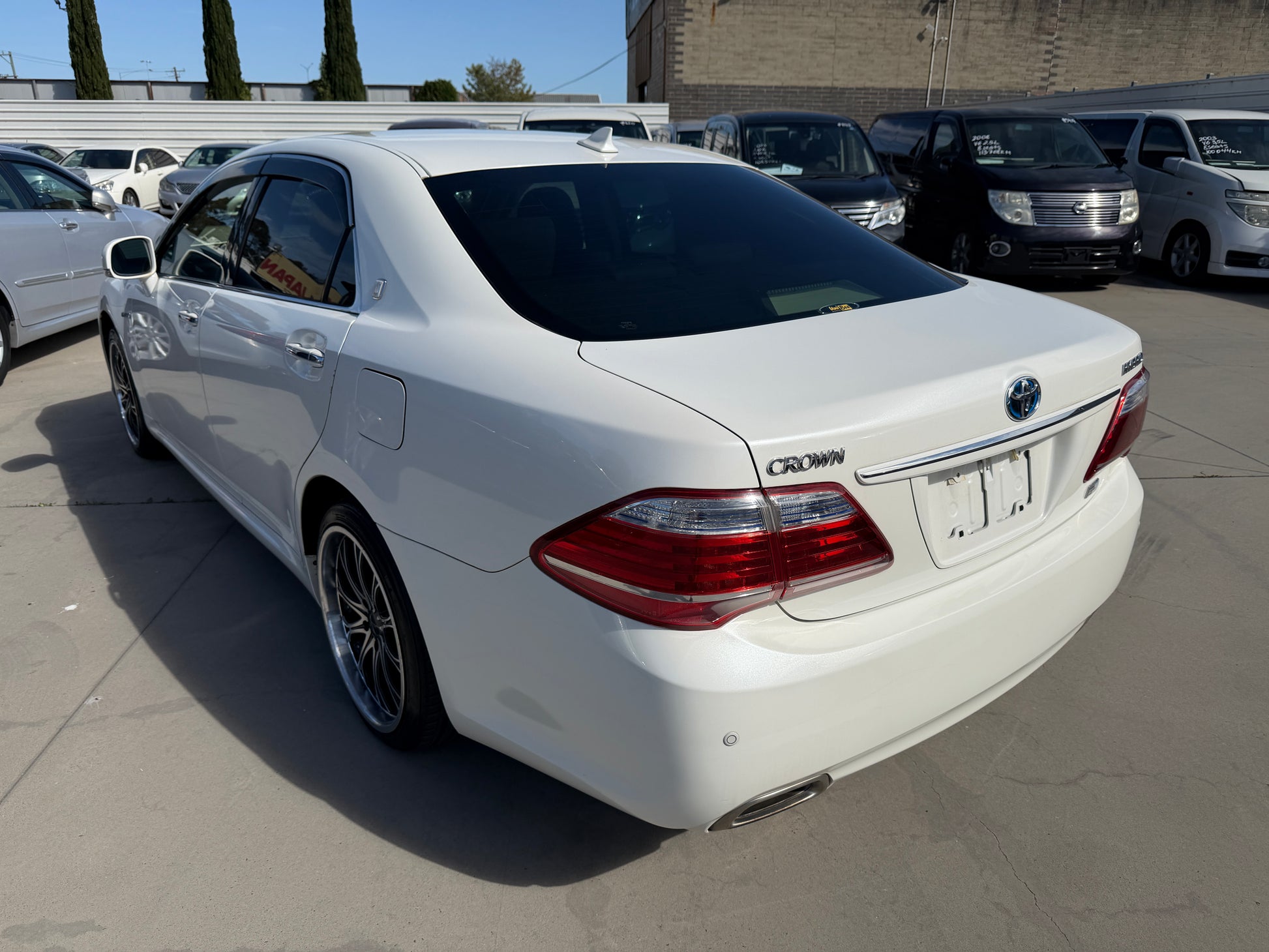 2012 Toyota Crown V6 3.5L Hybrid luxury sedan showcased in white color from rear view with alloy wheels and a clean exterior.