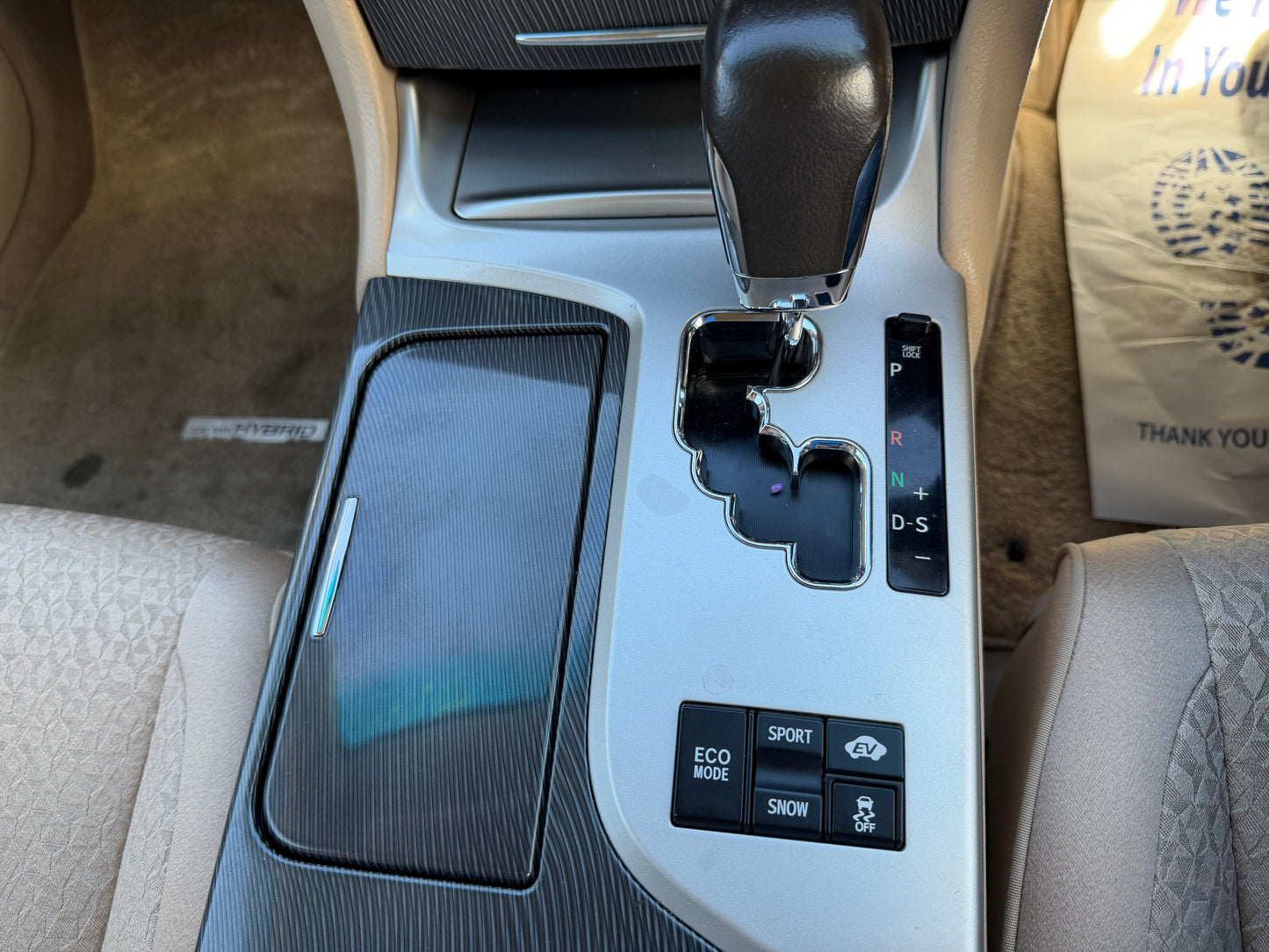 Interior console of a 2012 Toyota Crown V6 3.5L Hybrid Luxury Sedan showing gear selector and control buttons.