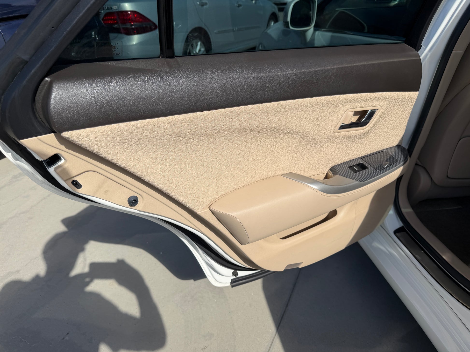 Interior door panel of a 2012 Toyota Crown V6 3.5L Hybrid luxury sedan, showcasing beige upholstery and controls.