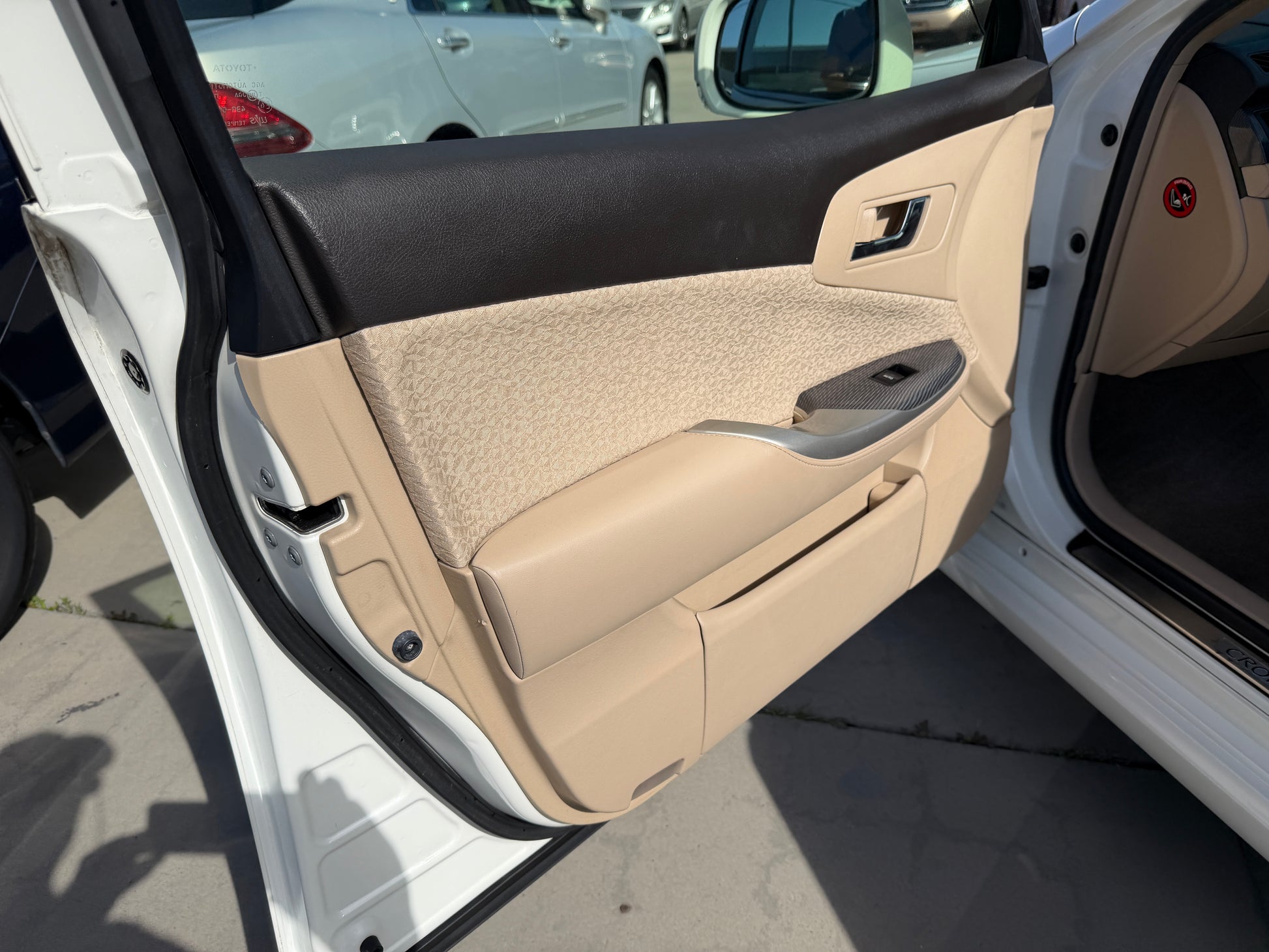 Interior view of the door panel of a 2012 Toyota Crown V6 3.5L Hybrid Luxury Sedan, featuring beige upholstery and controls.