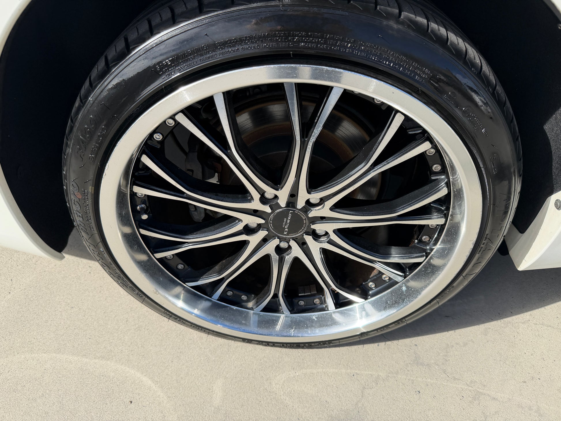 2012 Toyota Crown V6 3.5L Hybrid Close-up of a stylish alloy wheel with a polished rim and intricate spoke design on a luxury sedan tire.