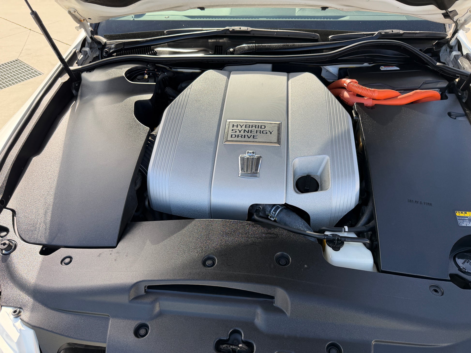 Engine compartment of a 2012 Toyota Crown V6 3.5L Hybrid showing the Hybrid Synergy Drive system.