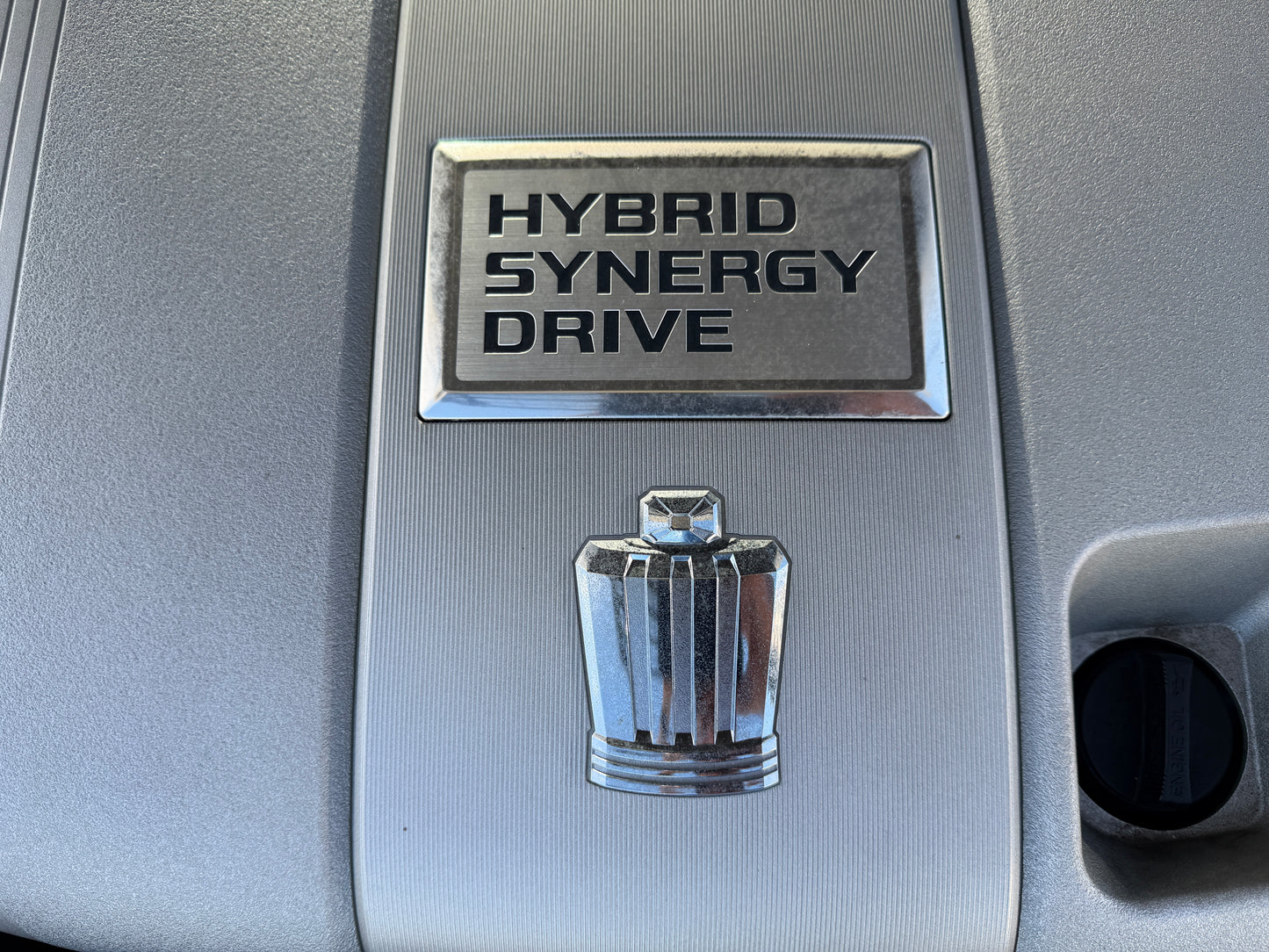 2012 Toyota Crown V6 3.5L Hybrid HYBRID SYNERGY DRIVE emblem on a vehicle's engine cover