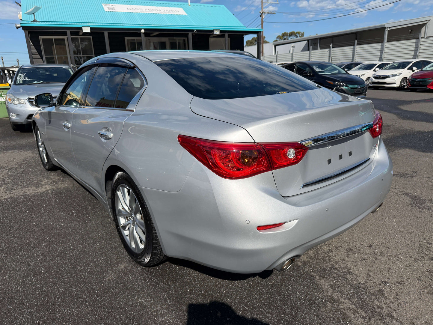 2014 Nissan Skyline V6 3.5L Hybrid parked in a dealership lot, showcasing elegant design and features optimal for luxury driving.
