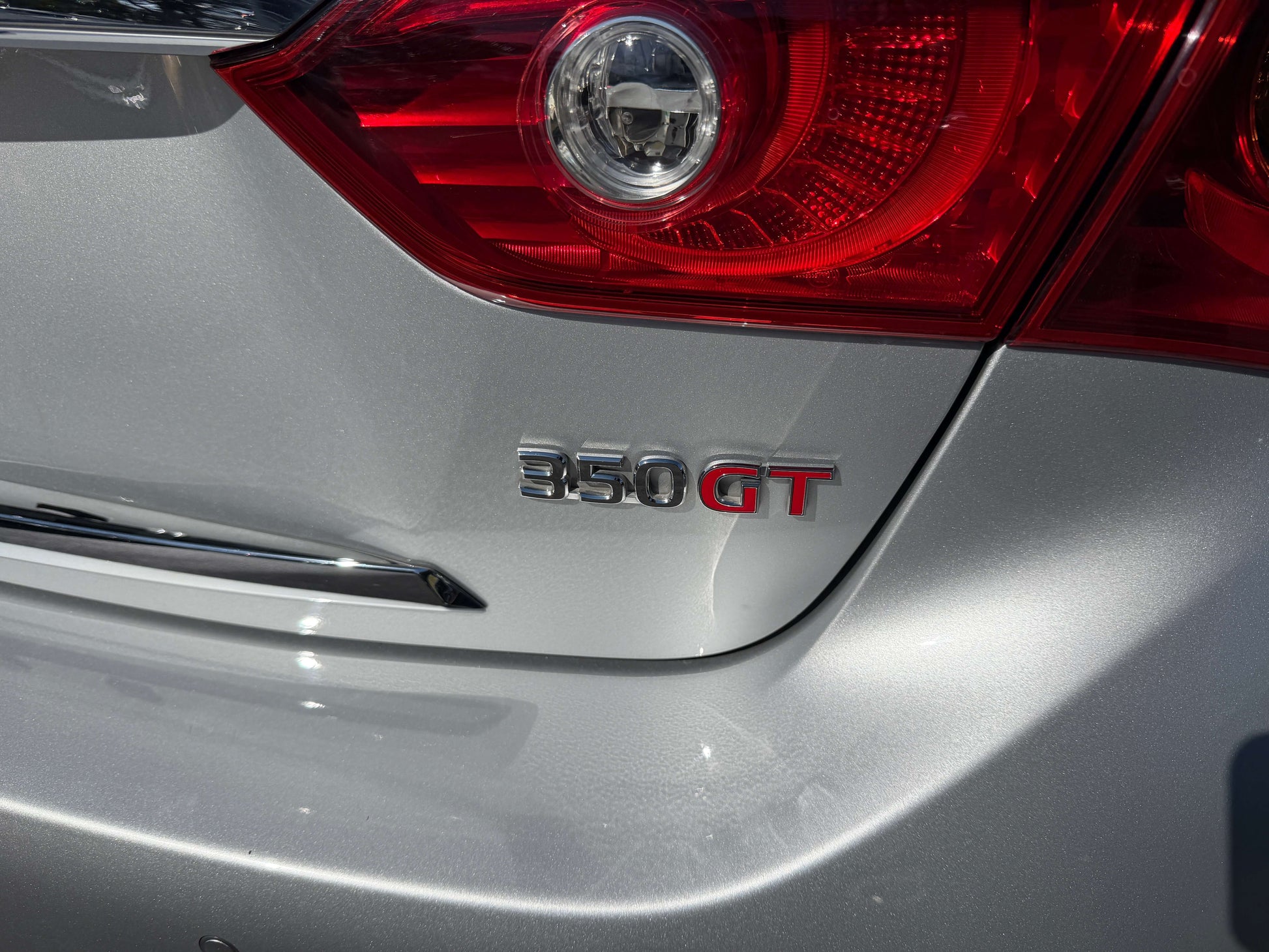 2014 Nissan Skyline V6 3.5L Hybrid badge with 350GT lettering on the rear of a silver sedan
