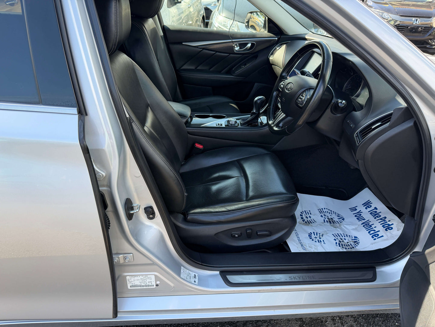 Interior view of 2014 Nissan Skyline V6 3.5L Hybrid showing black leather seats and dashboard.