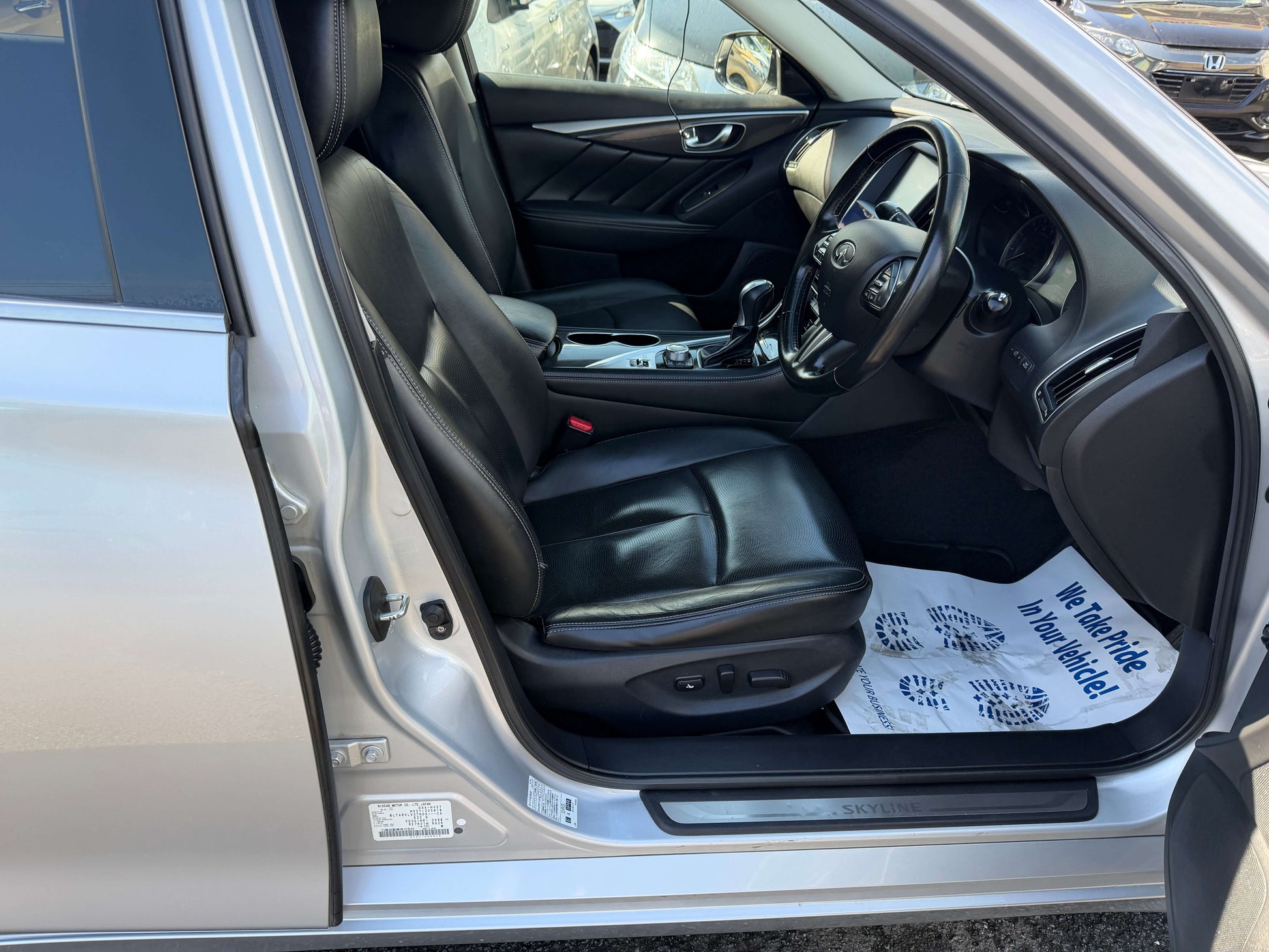 Interior view of 2014 Nissan Skyline V6 3.5L Hybrid showing black leather seats and dashboard.
