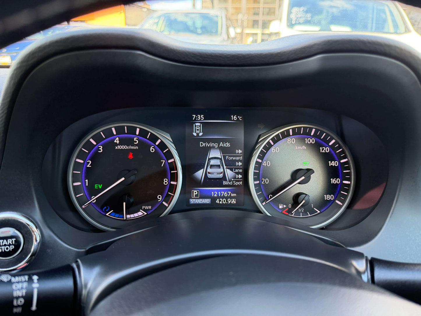 Dashboard display of a 2014 Nissan Skyline V6 3.5L Hybrid showcasing speedometer, EV indicator, and driving aids.