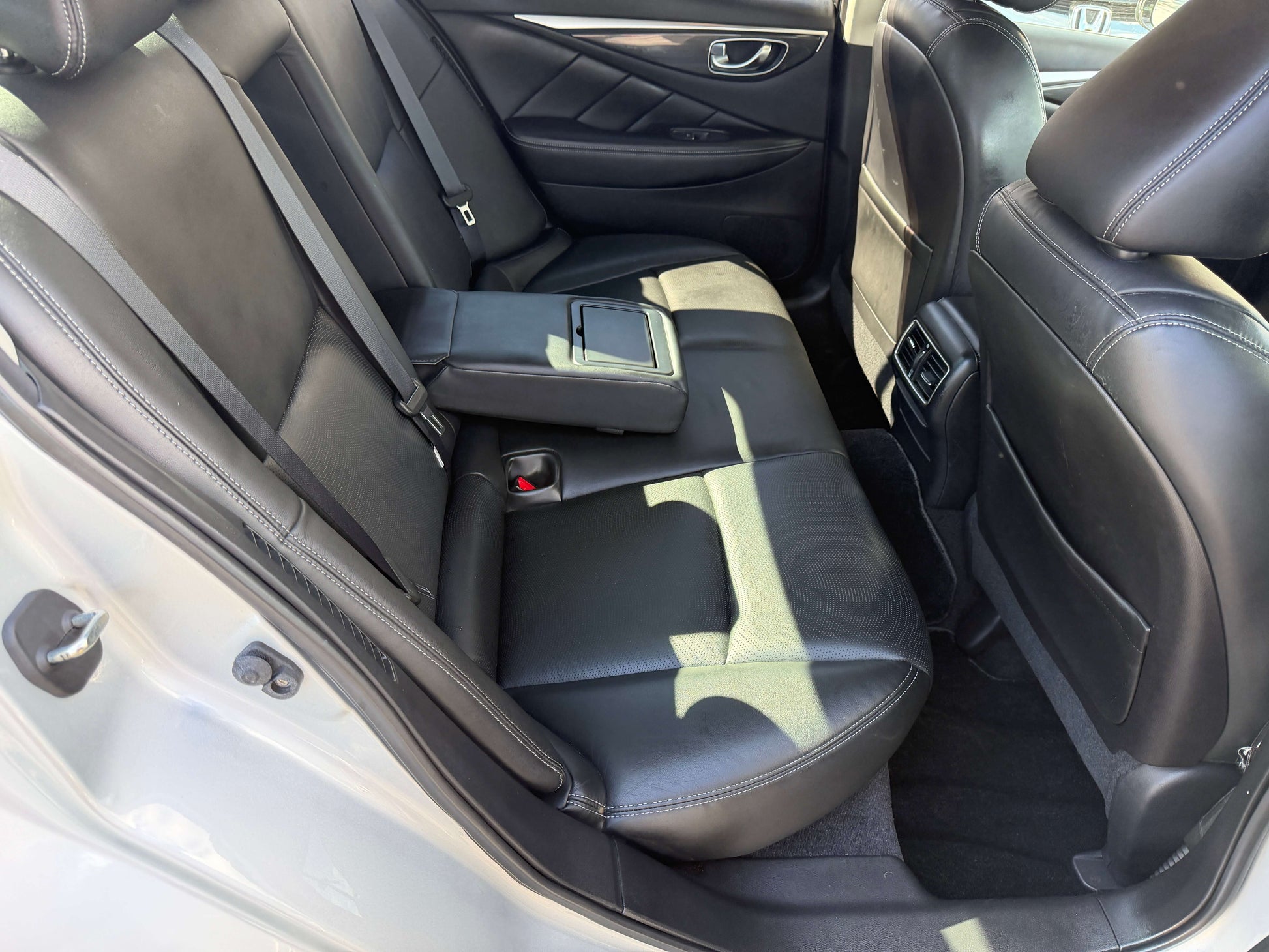 Interior view of the back seat of a 2014 Nissan Skyline V6 3.5L Hybrid, showcasing luxurious leather seating.