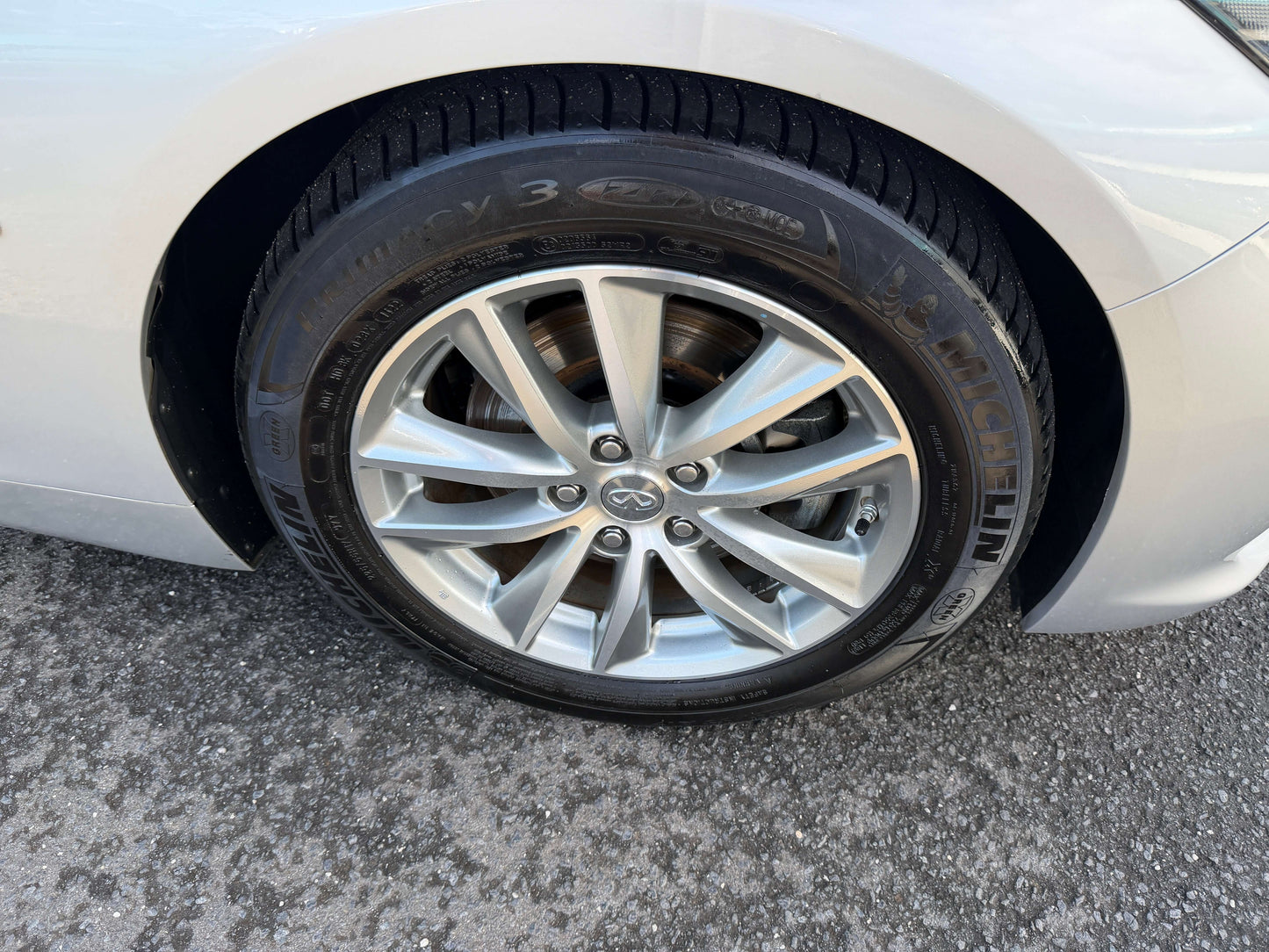 2014 Nissan Skyline V6 3.5L Hybrid sporty alloy wheel close-up with Michelin tire on asphalt.