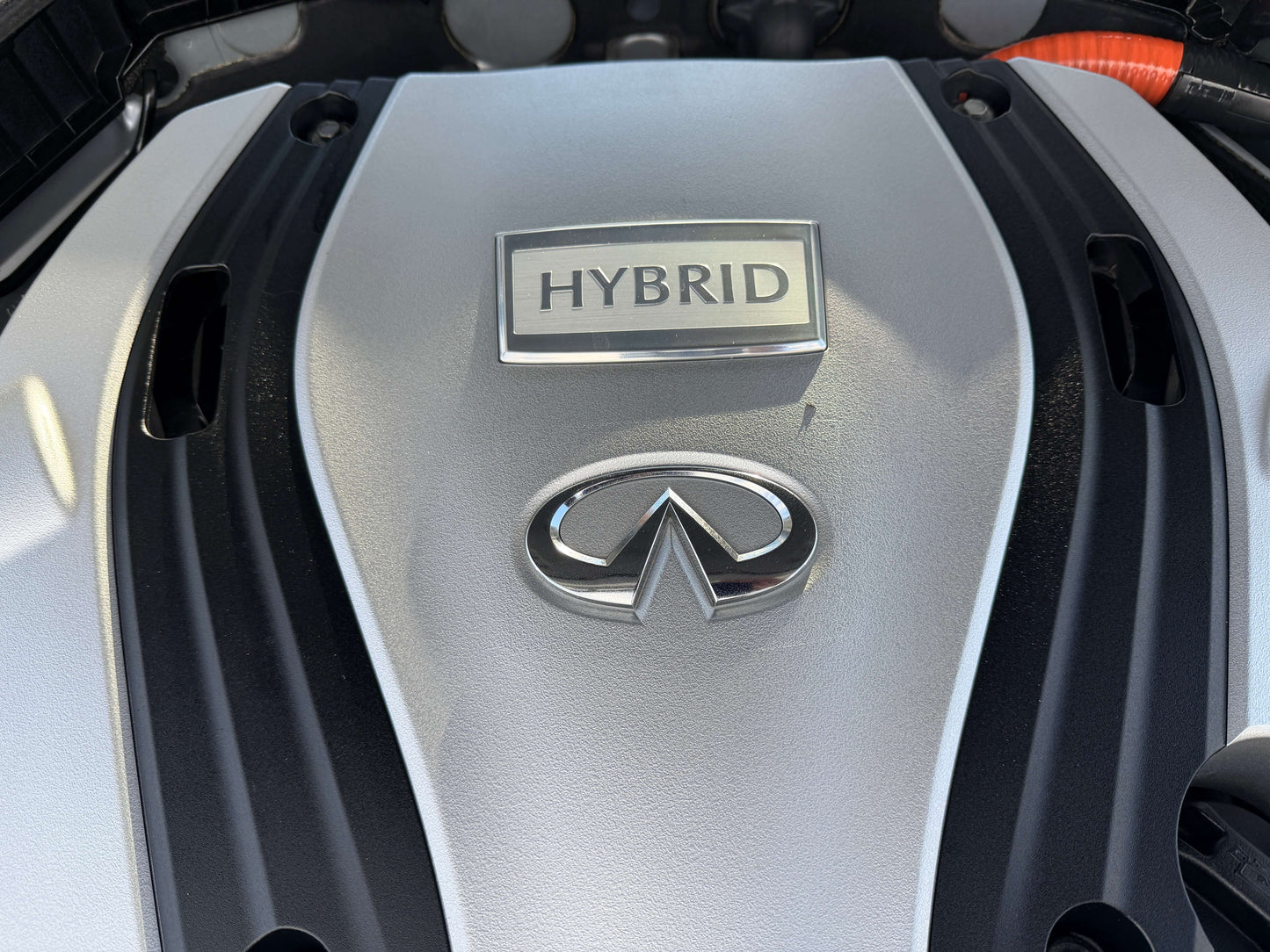 Close-up of the 2014 Nissan Skyline V6 3.5L Hybrid engine cover showing the Infiniti logo and hybrid badge.