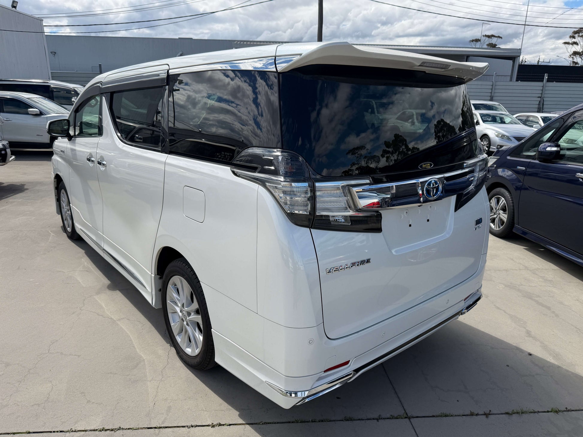 2015 Toyota Vellfire 2.5L e-Four Hybrid rear view showcasing luxury design and spaciousness in a white exterior.