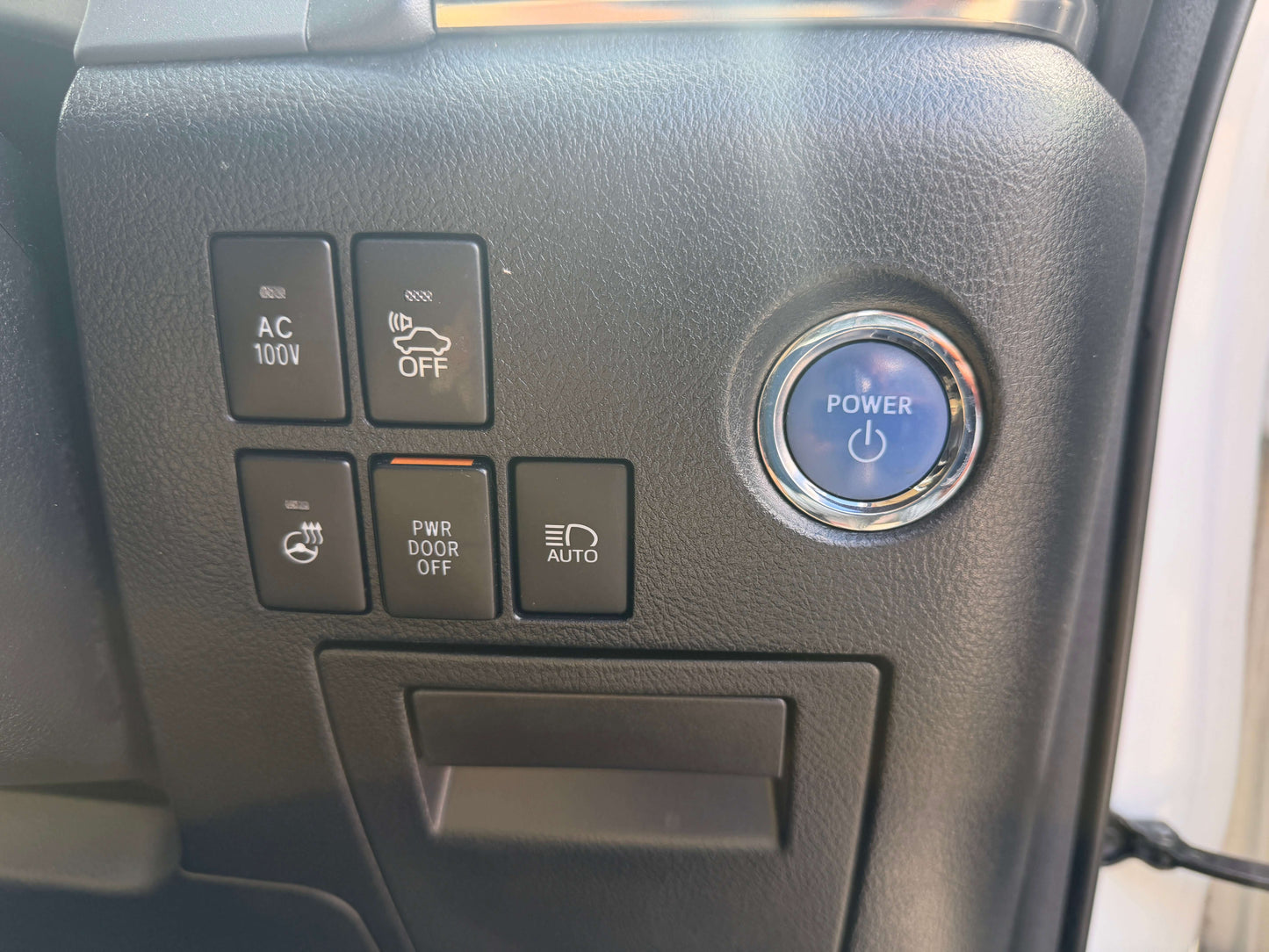 Interior control panel of a 2015 Toyota Vellfire 2.5L e-Four Hybrid with power button, AC options, and door controls