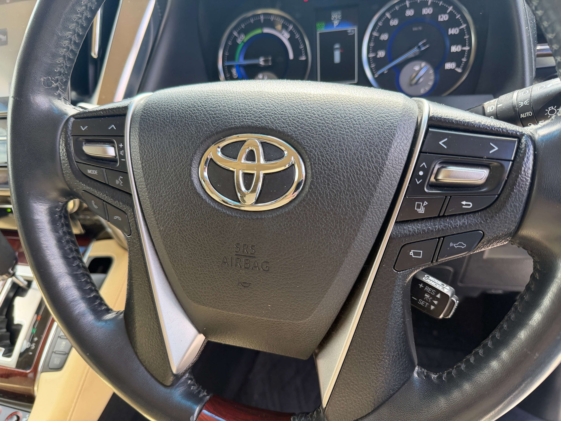 Interior view of the 2015 Toyota Vellfire 2.5L e-Four Hybrid steering wheel with controls and dashboard display.