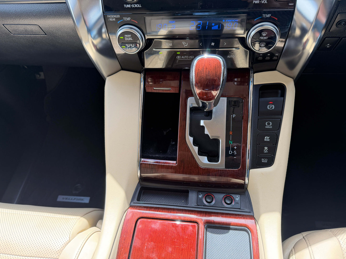 Interior view of the 2015 Toyota Vellfire 2.5L e-Four Hybrid dashboard with gear shift and controls.