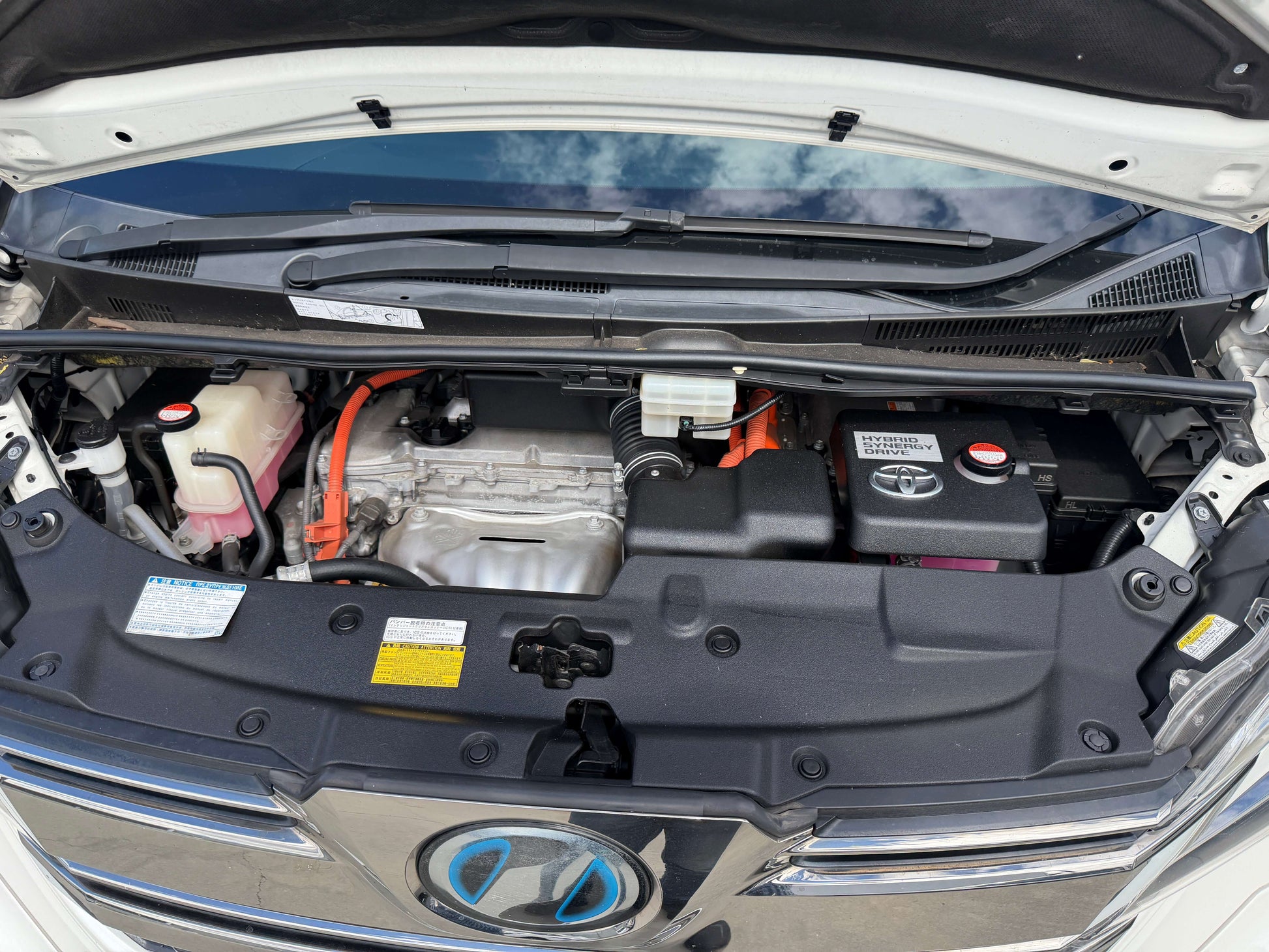 Engine bay of a 2015 Toyota Vellfire 2.5L e-Four Hybrid showing hybrid components and battery.
