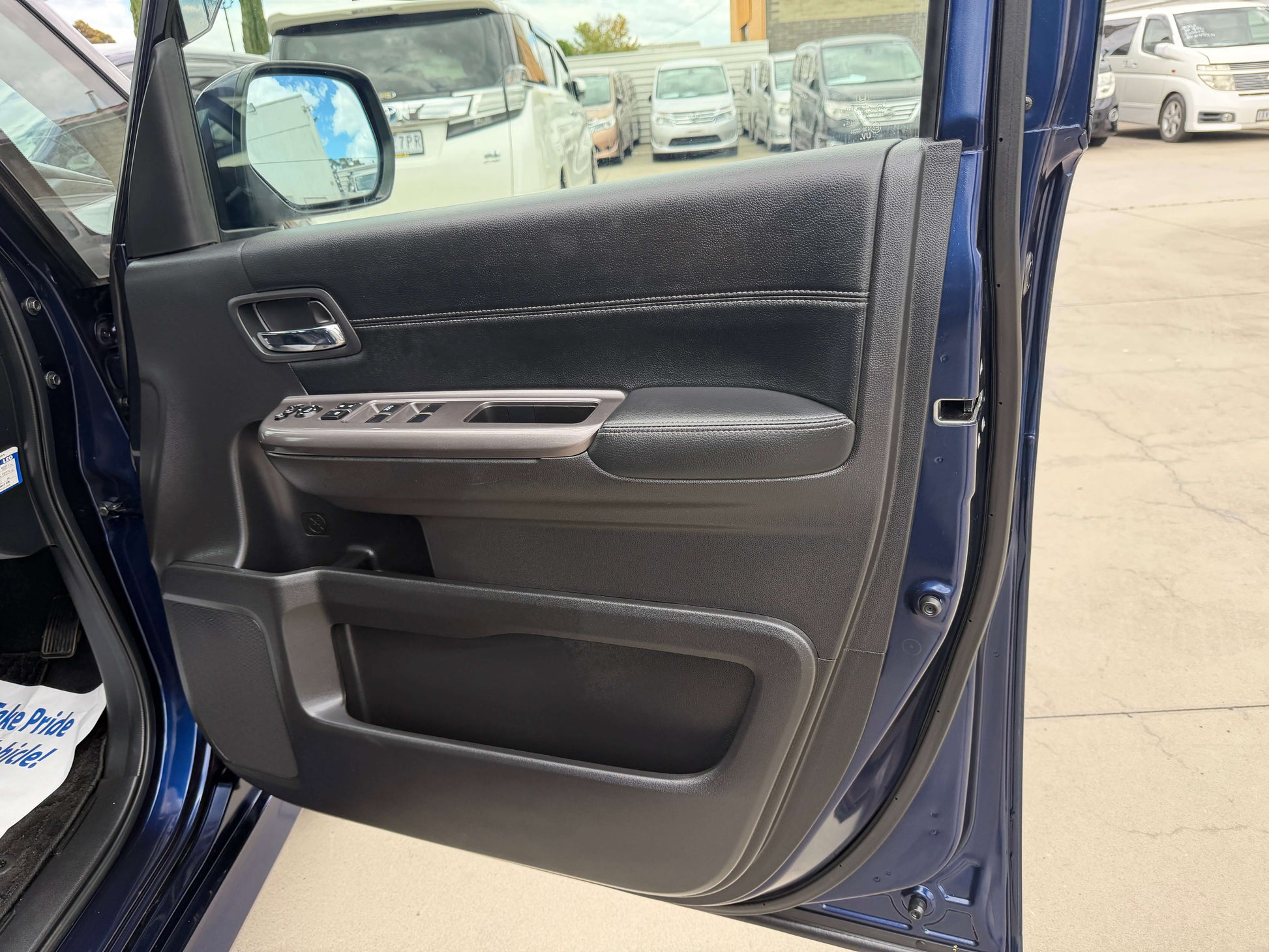 Interior view of the 2018 Honda Honda Stepwgn 2.0 Spada Hybrid G EX door panel with controls and black leather trim.