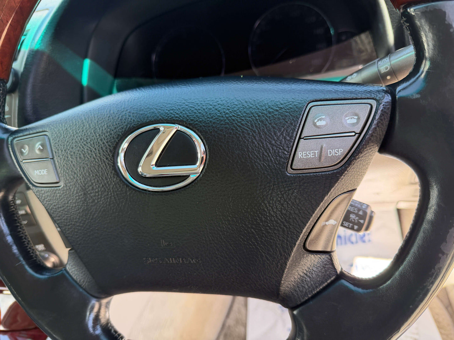 Close-up of the steering wheel of a 2007 Lexus LS600hL AWD V8 5.0L Hybrid, featuring the Lexus logo and controls.