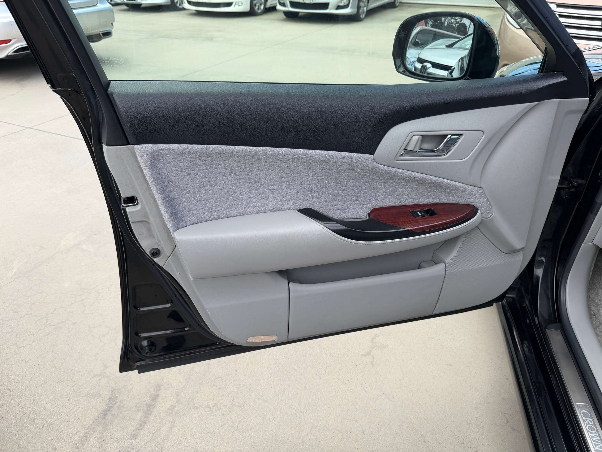 Interior view of the 2008 Toyota Crown V6 3.0L Royal Saloon sedan door with grey upholstery and wooden trim.
