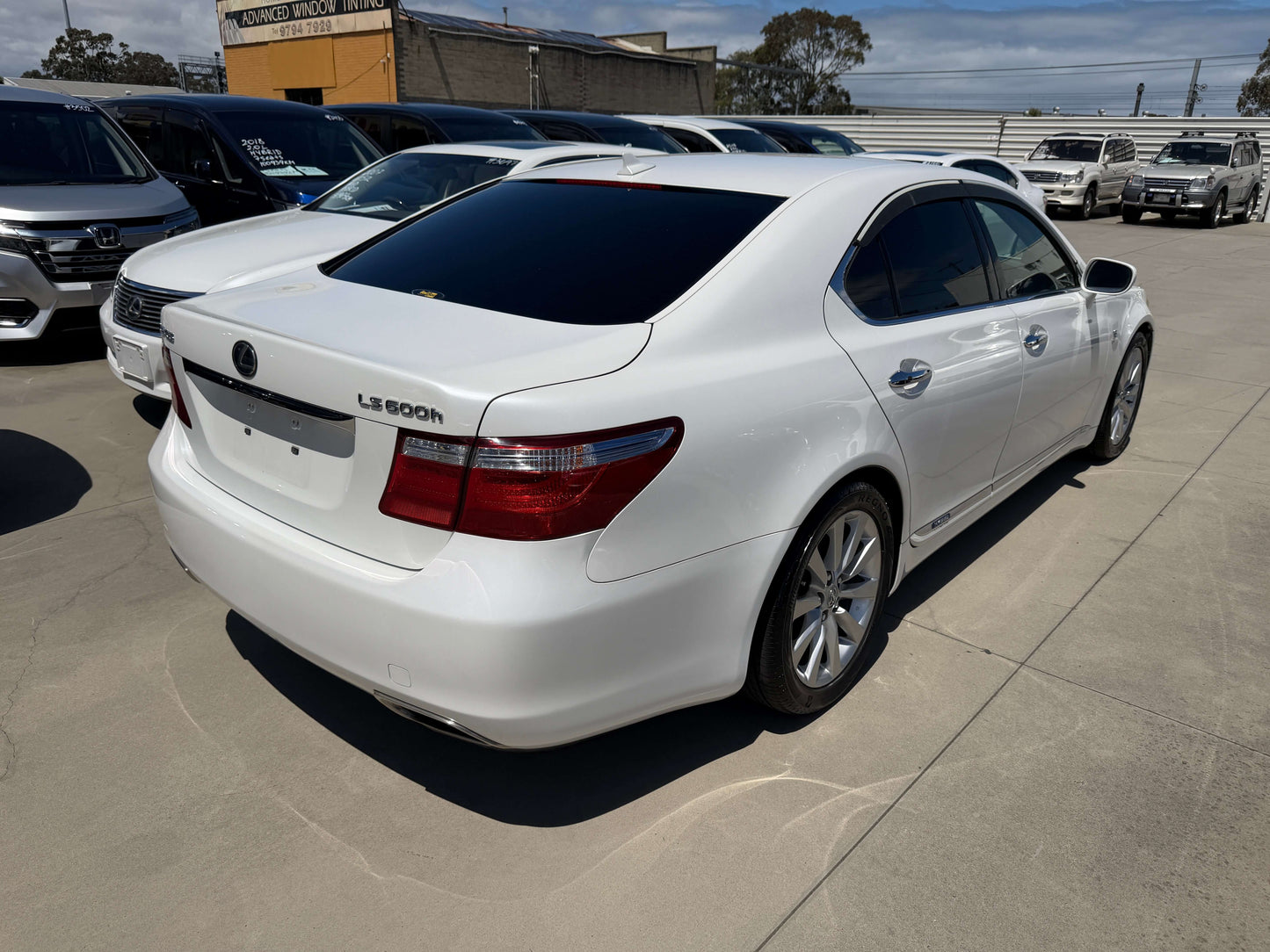 2007 Lexus LS600h AWD V8 5.0L Hybrid luxury sedan in pearl white viewed from the rear.