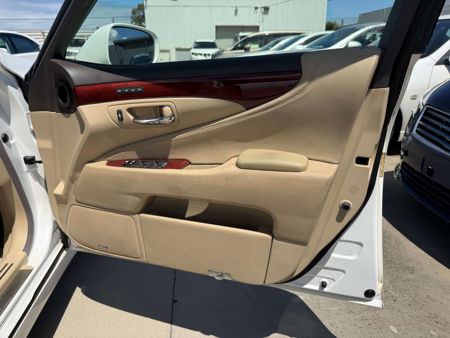 Interior view of the 2007 Lexus LS600h AWD V8 5.0L Hybrid luxury sedan door panel with cream leather and wood accents.