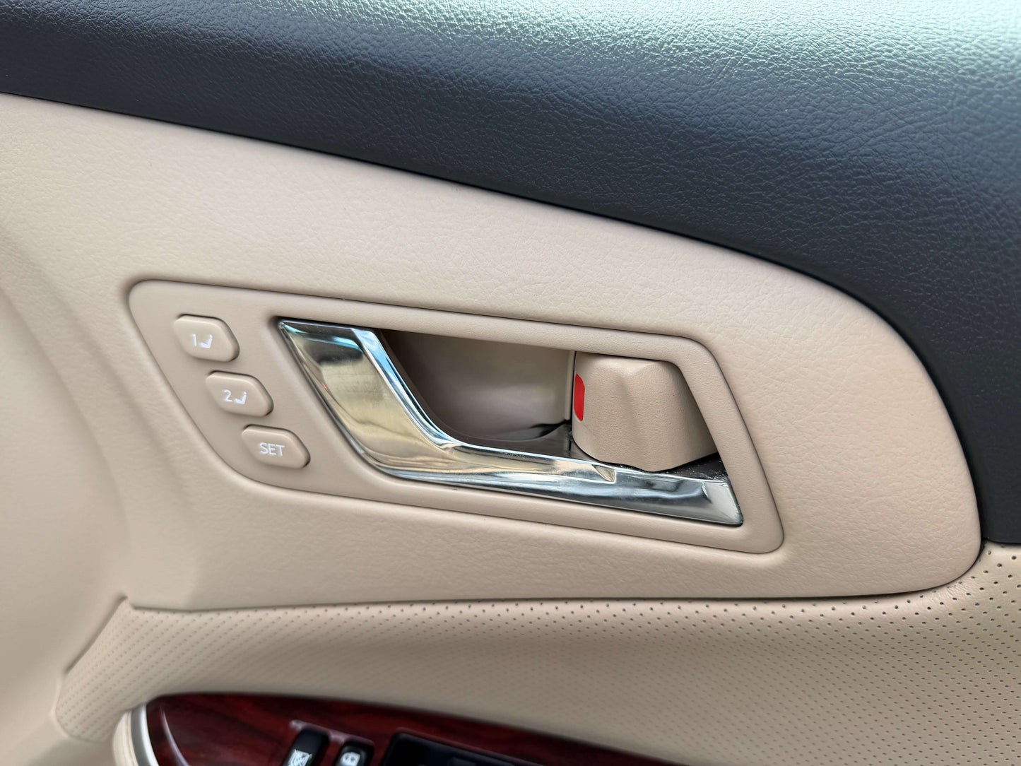 Interior view of the door handle and seat adjustment controls in a 2010 Toyota Crown V6 3.0L Royal Saloon G Edition.