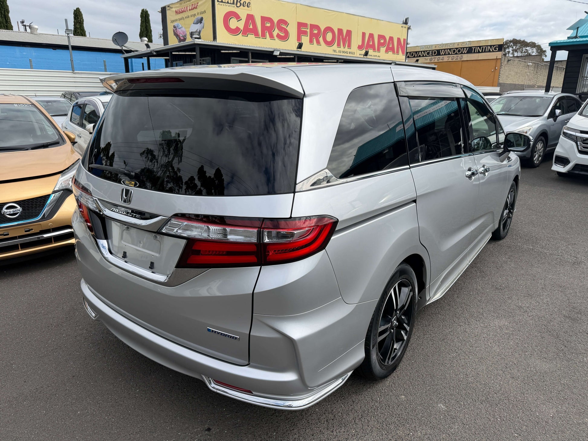 2016 Honda Odyssey 2.0 Hybrid parked at a dealership showing its sleek silver design and family-friendly features.