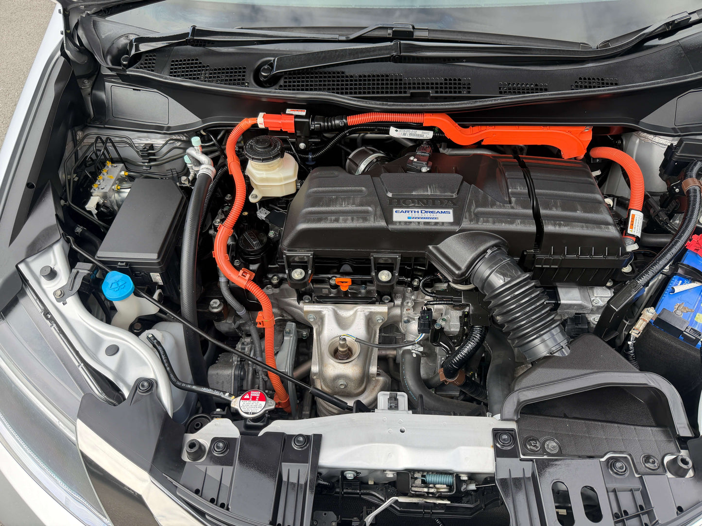 Engine compartment of a 2016 Honda Odyssey 2.0 Hybrid showcasing hybrid technology and components.