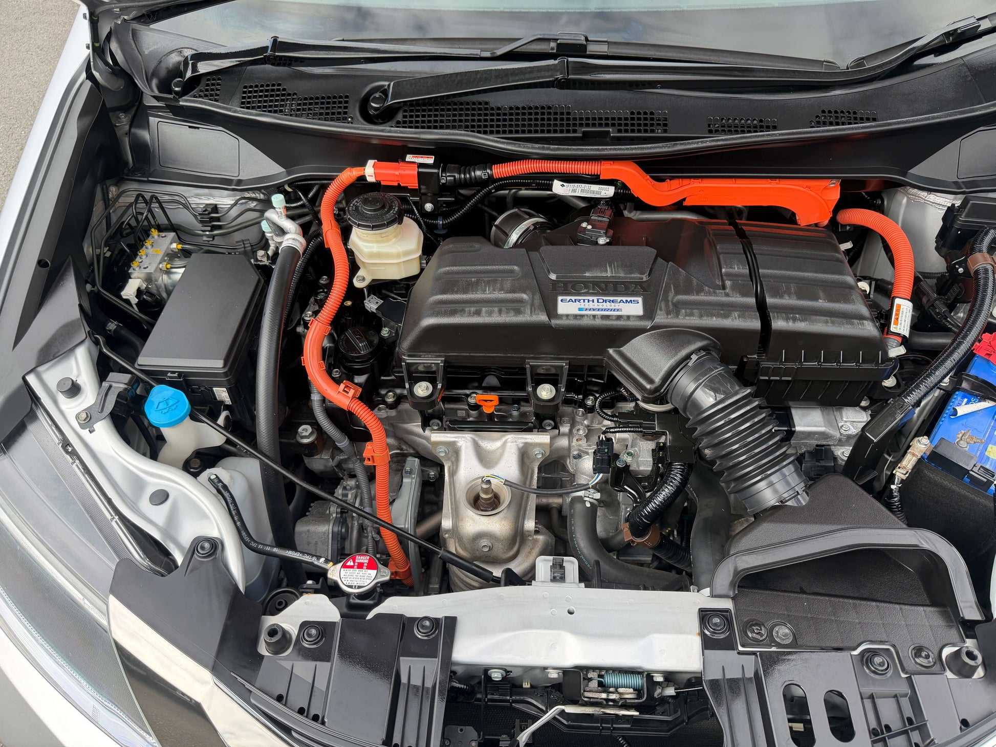 Engine compartment of a 2016 Honda Odyssey 2.0 Hybrid showcasing hybrid technology and components.