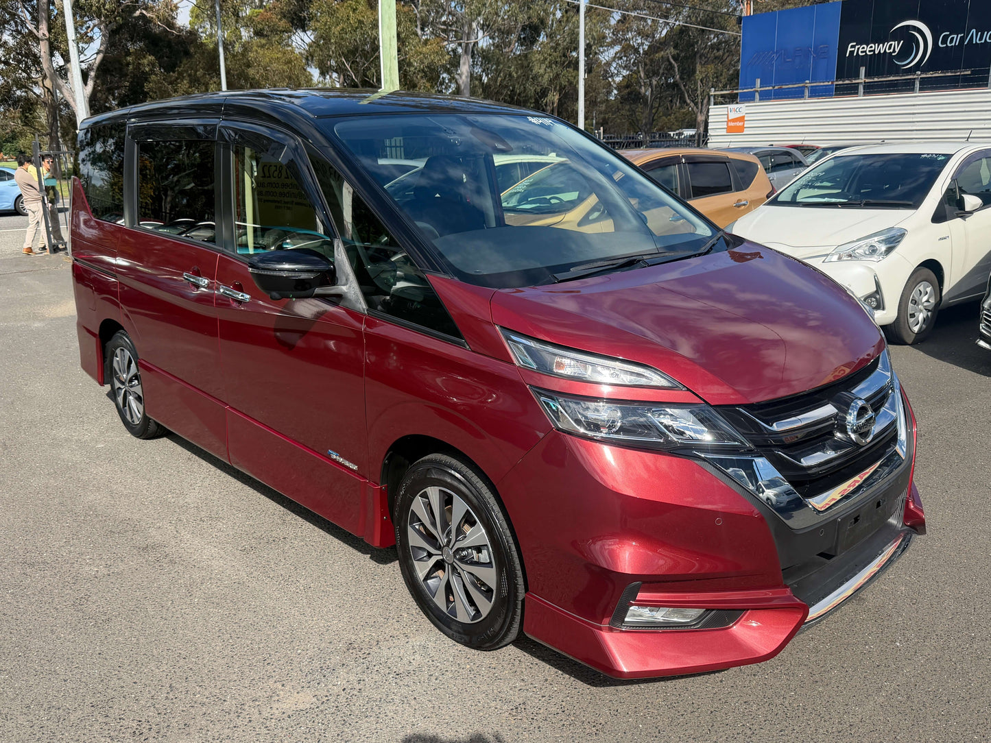 2016 Nissan Serena 2.0L S-Hybrid Highway Star Edition in red with 8 seats, front view at a car dealership.
