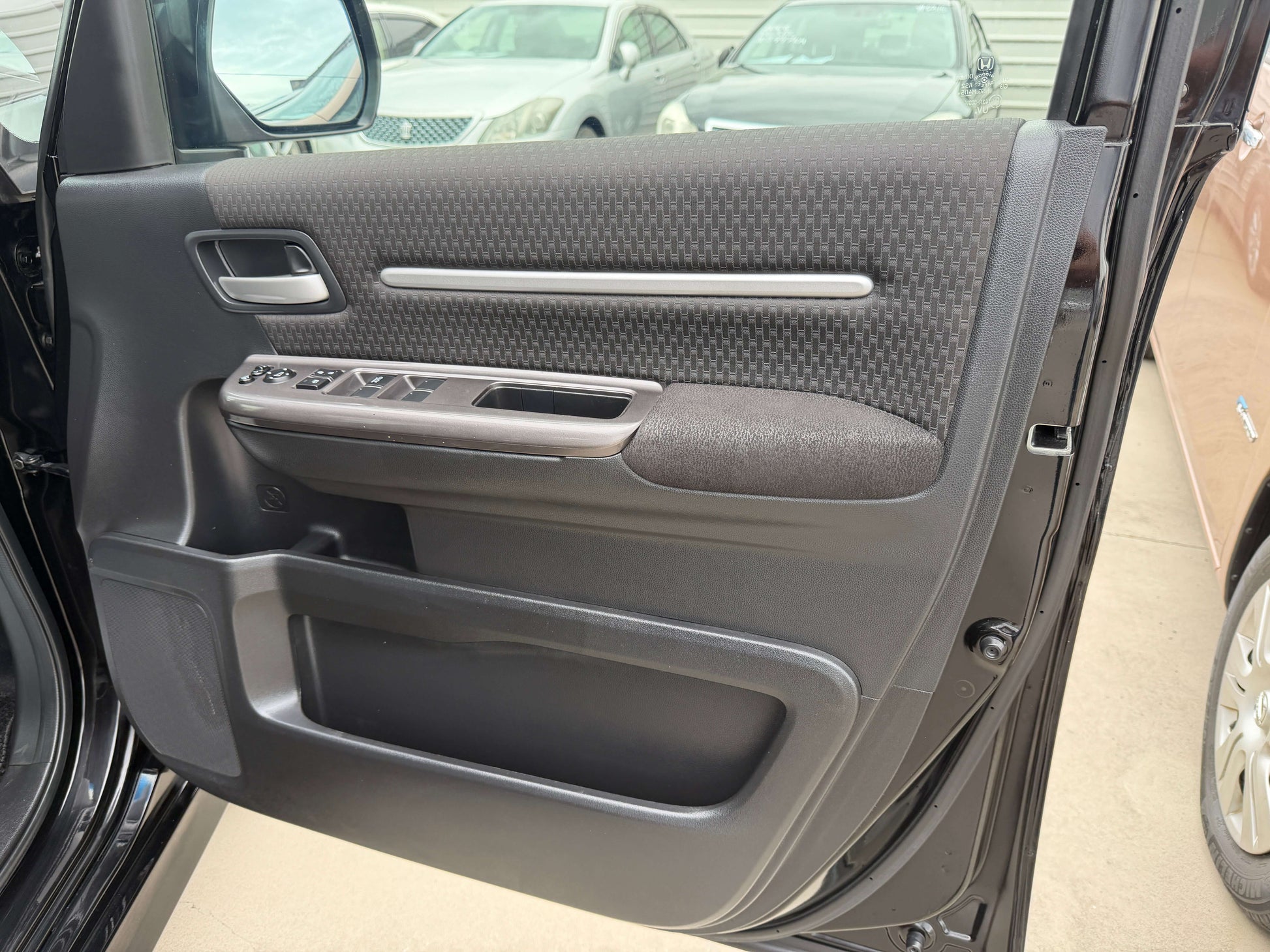 Interior view of the door panel of a 2018 Honda Stepwgn 2.0 Spada Hybrid, showcasing handle and controls.
