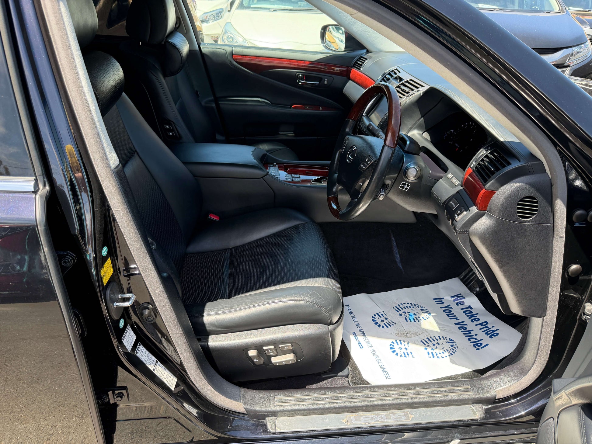 Interior view of 2007 Lexus LS600hL AWD V8 5.0L Hybrid Luxury Sedan showing black leather seats and dashboard details.