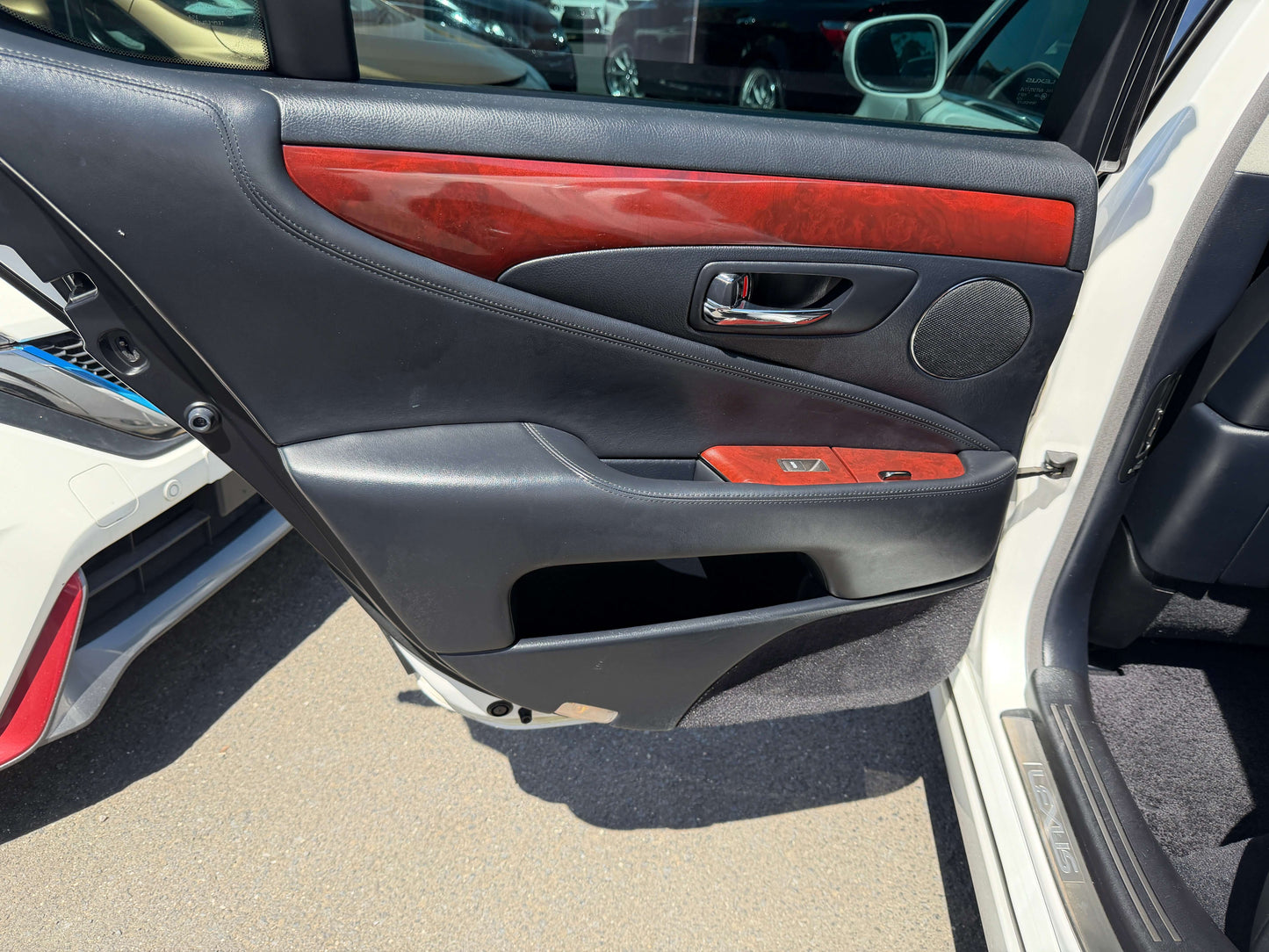 Interior view of the 2007 Lexus LS600h AWD V8 5.0L Hybrid luxury sedan door panel featuring black leather and wood trim.