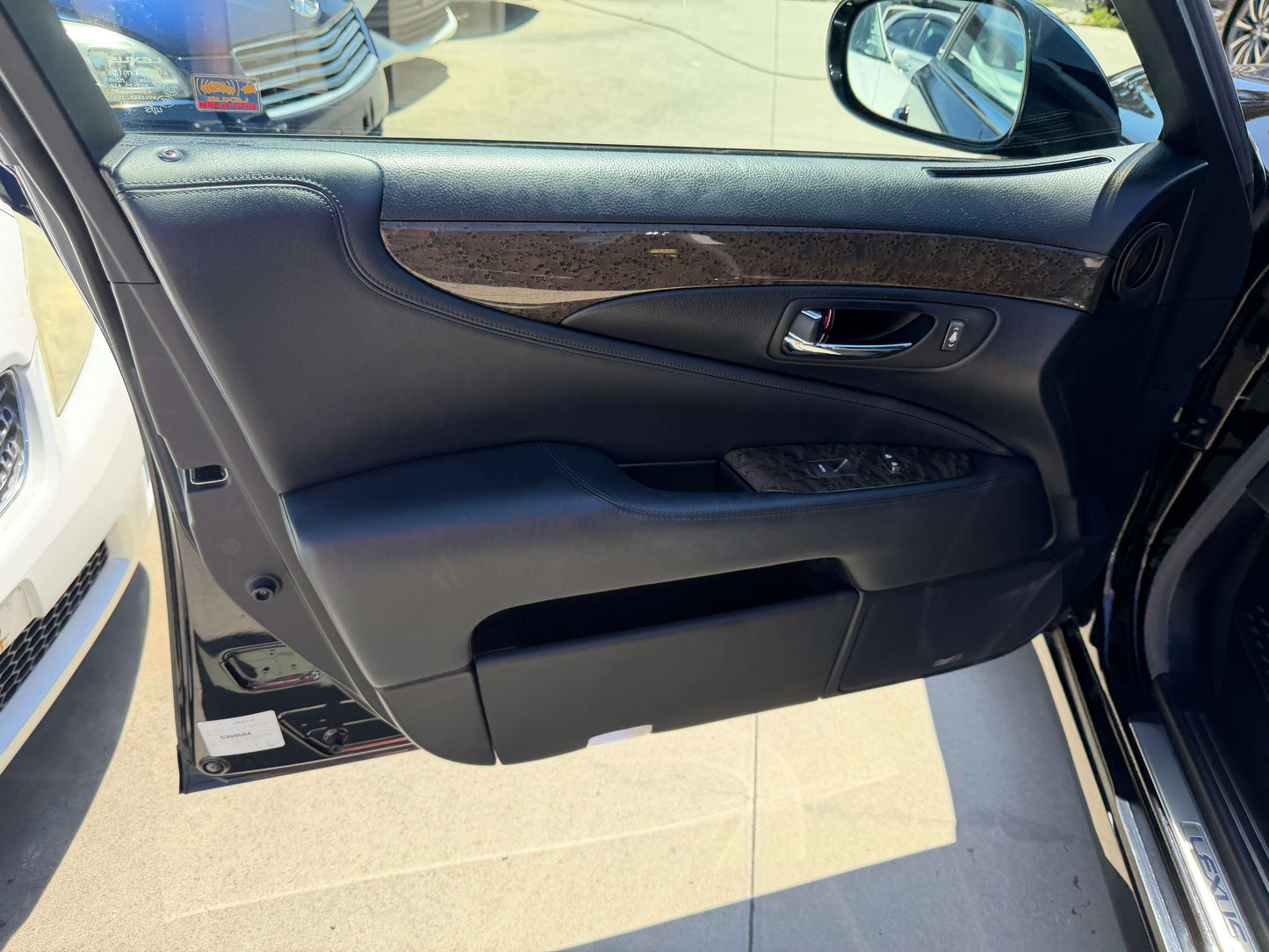 Interior view of the 2007 Lexus LS600h AWD V8 5.0L Hybrid door panel with black leather and wooden trim.