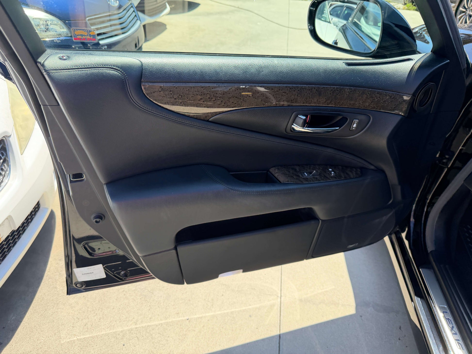 Interior view of the 2007 Lexus LS600h AWD V8 5.0L Hybrid door panel with black leather and wooden trim.