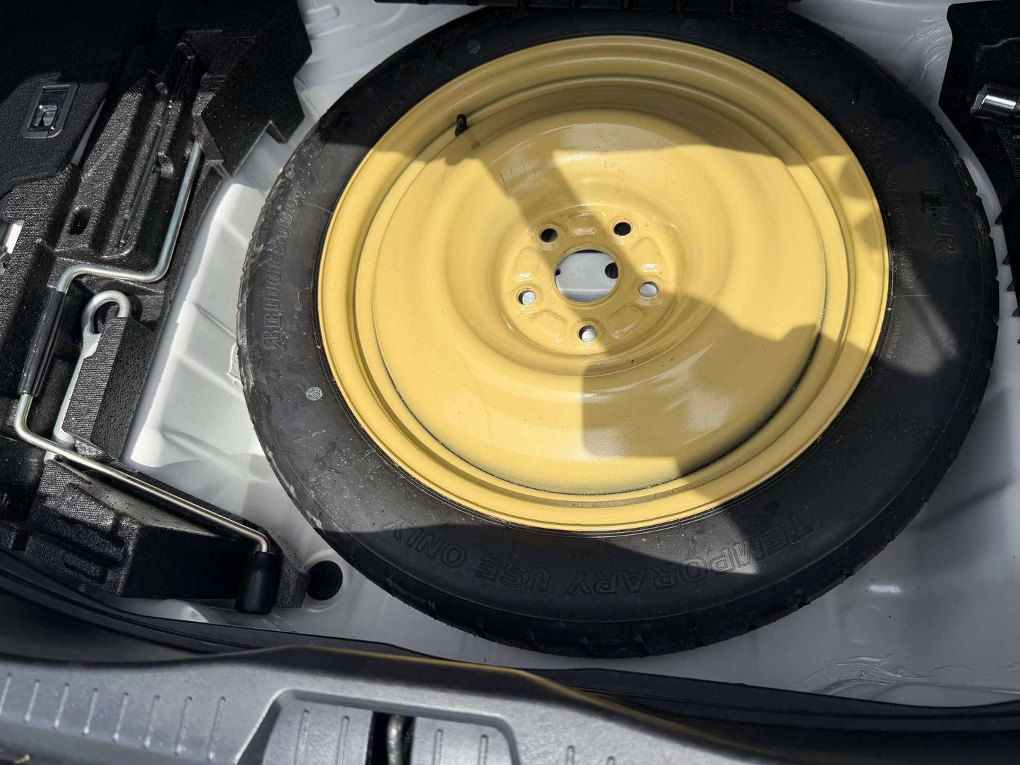 2007 Lexus LS460 V8 4.6L  Spare tire with yellow rim located in the trunk of a vehicle.